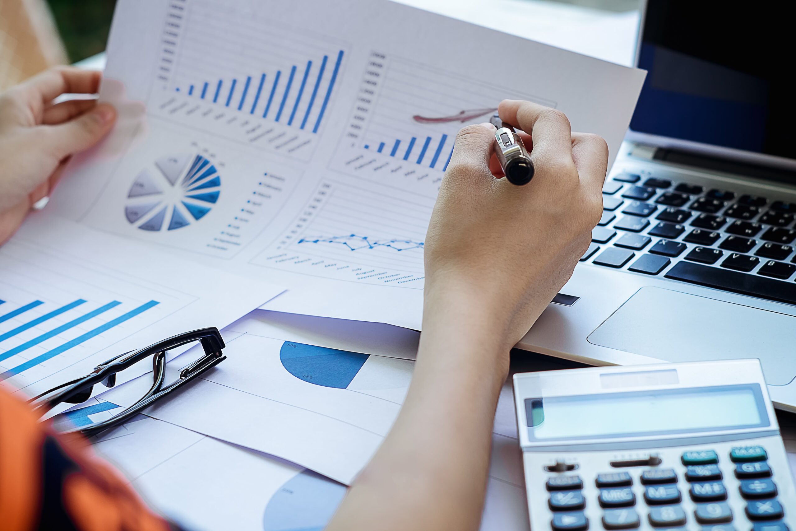 woman reviewing charts and graphs at a desk with a laptop and calculator