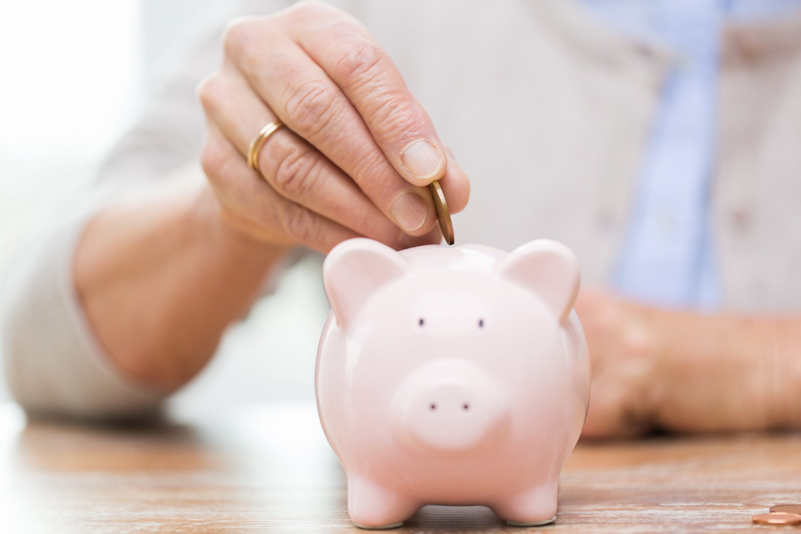 older woman putting coin in piggy bank