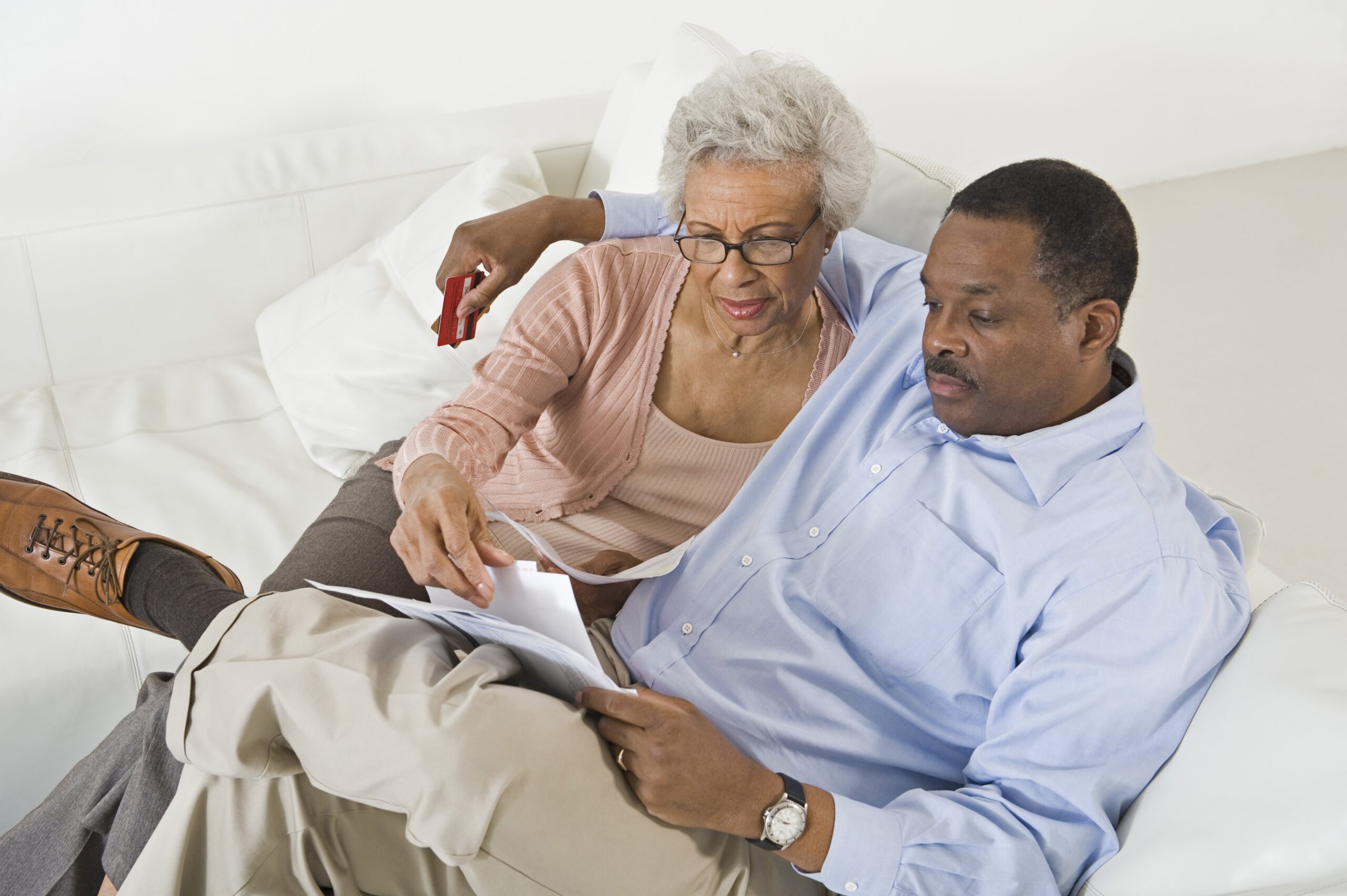 older couple sitting on couch reviewing monthly bills