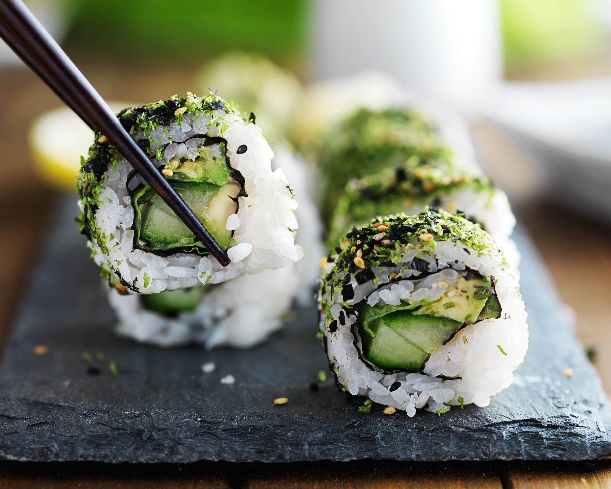 healthy kale and avocado sushi roll with chopsticks