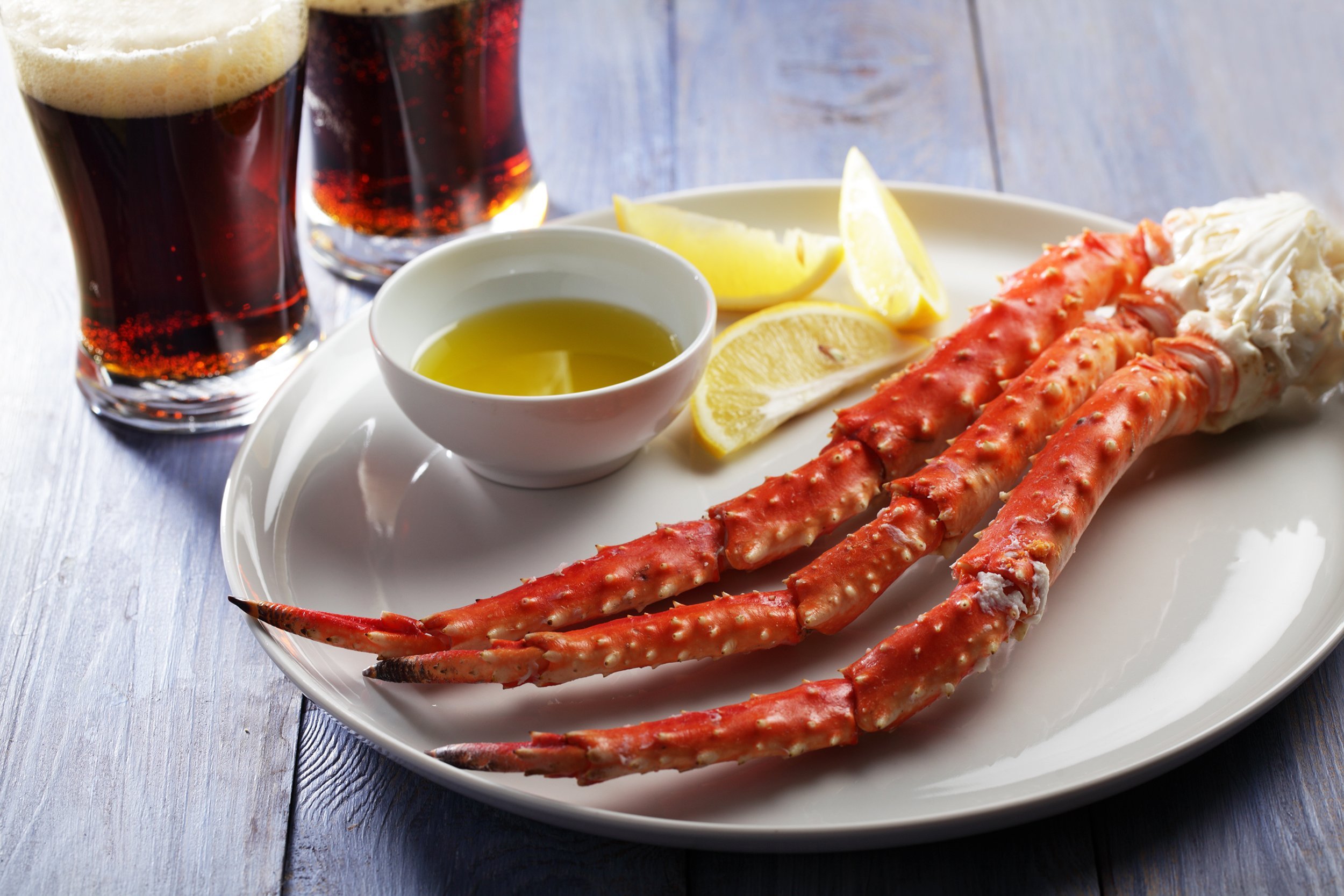 red king crab legs with lemon and porter beer on a rustic table