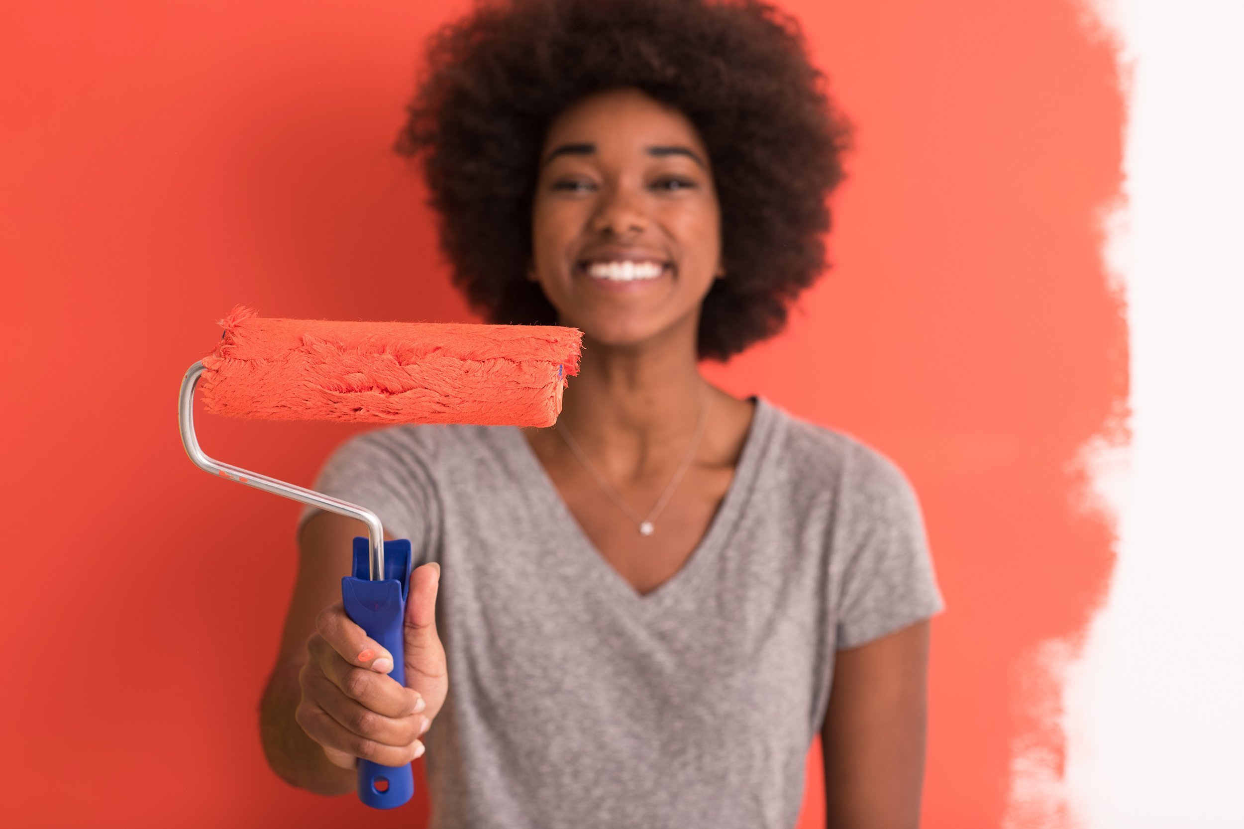 African American woman painting wall in her new apartment