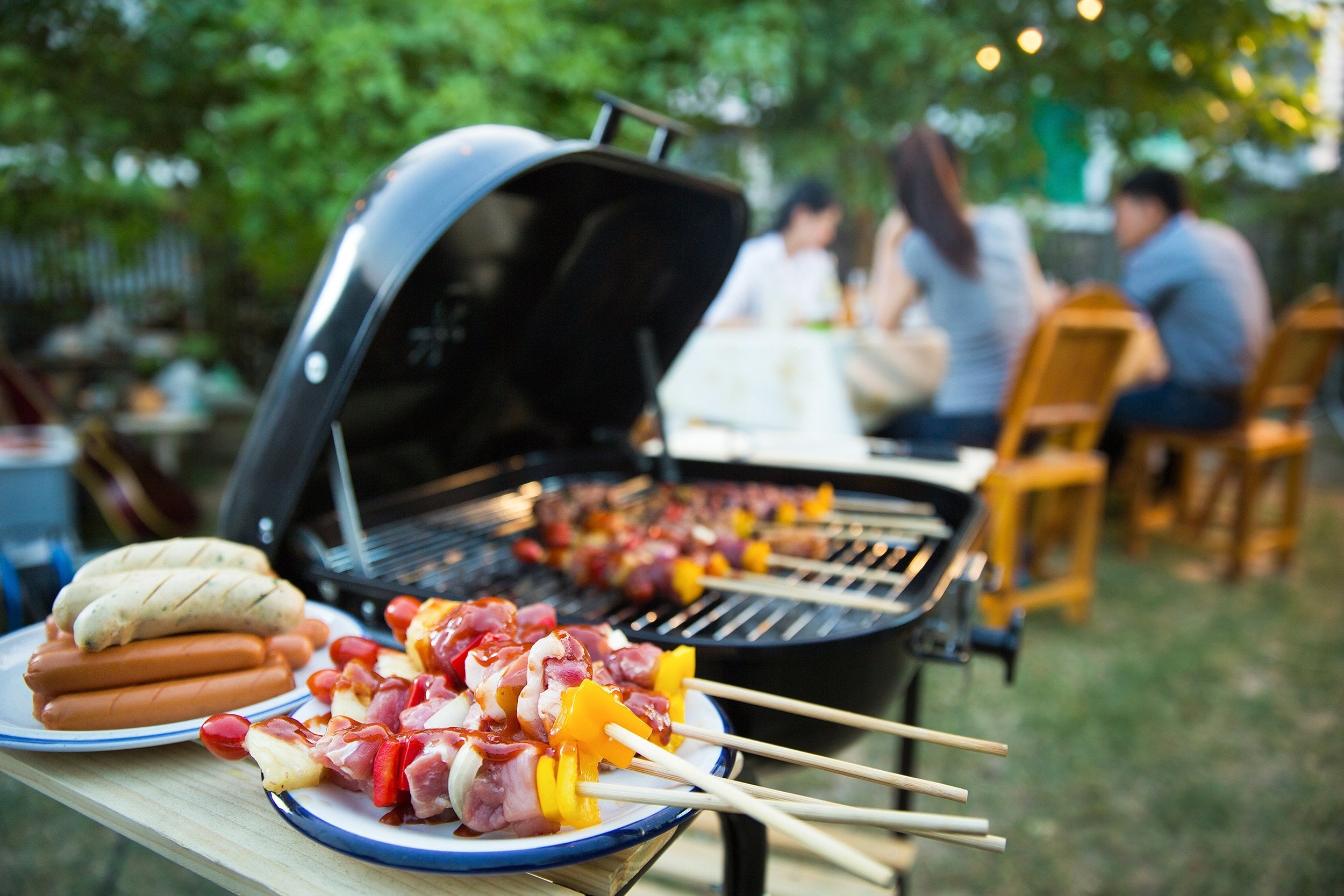charcoal grill with food and people in the background