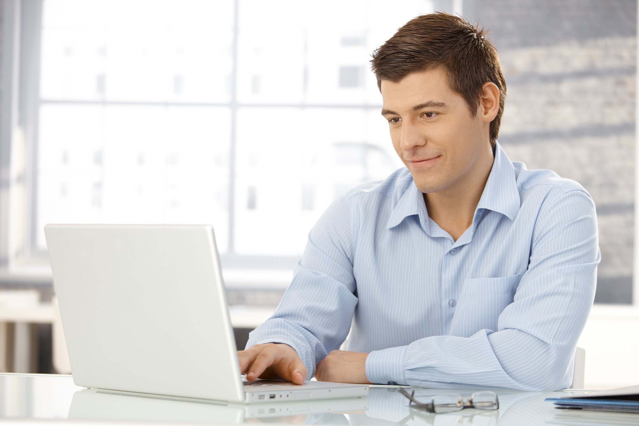 businessman working in office, sitting at desk, looking at laptop computer screen