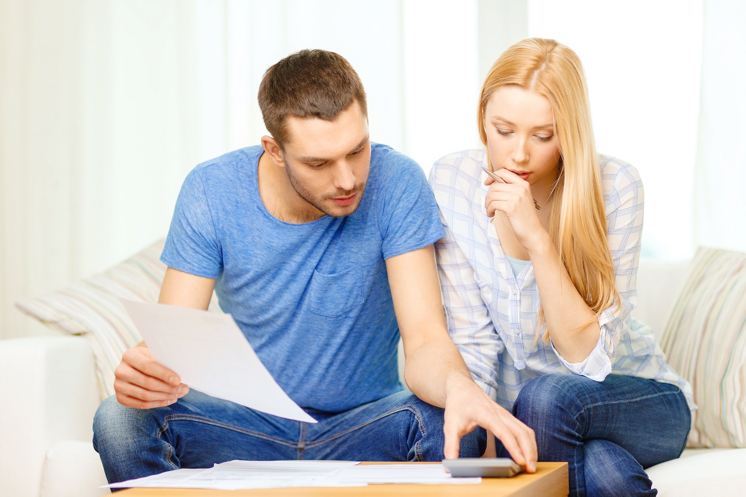 busy couple with papers and calculator at home