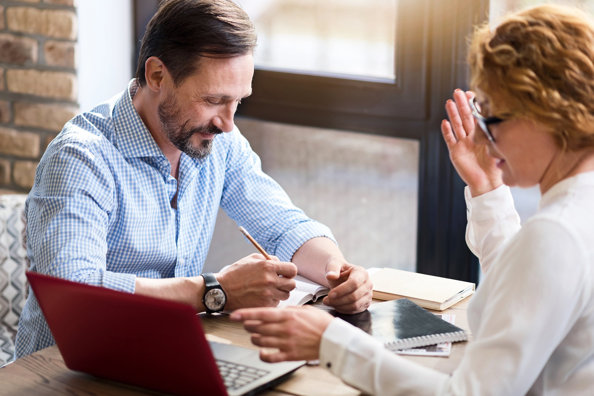 middle-aged couple working on laptop and taking notes