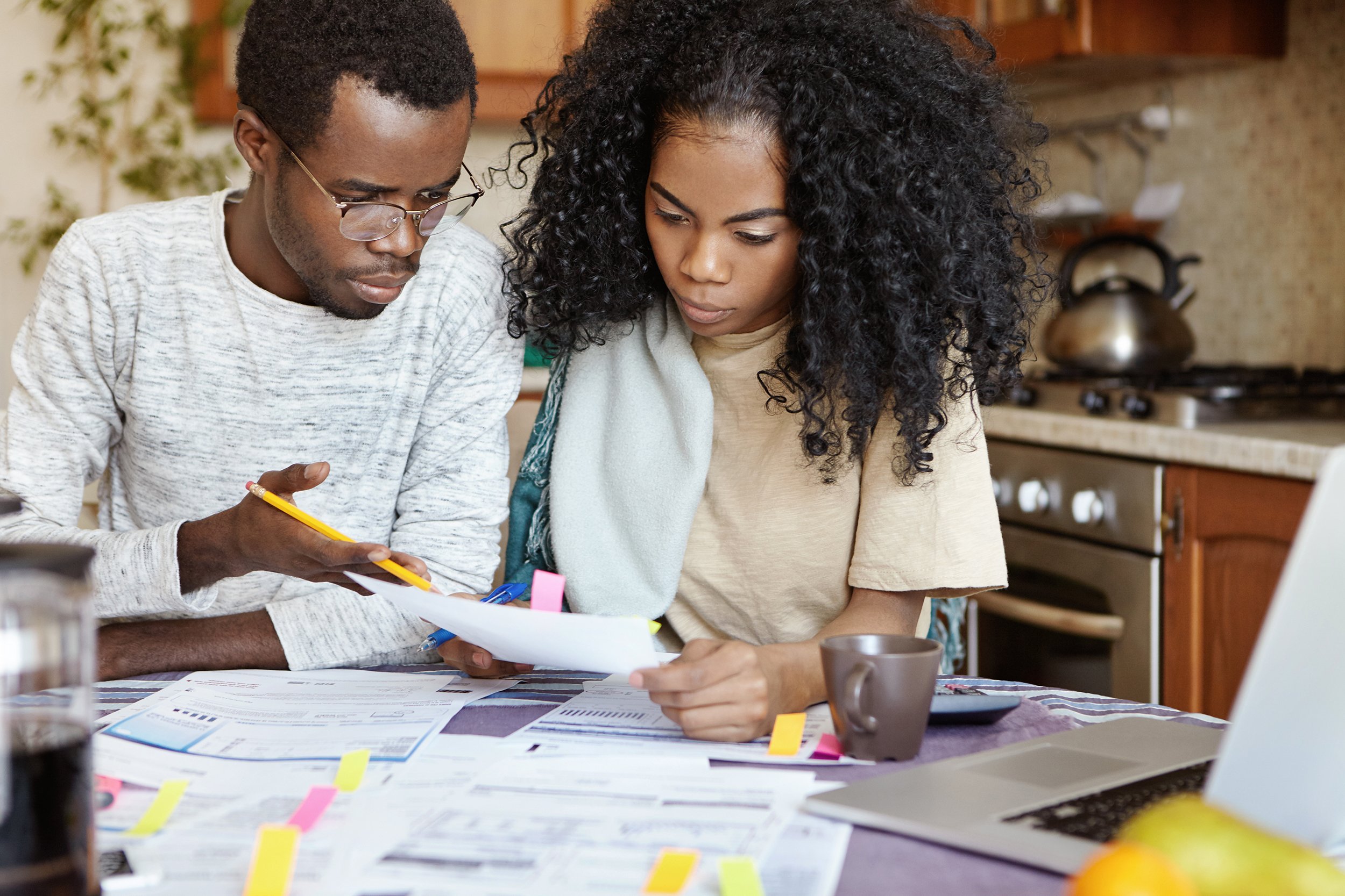 African American husband and wife looking over finances with laptop at kitchen table