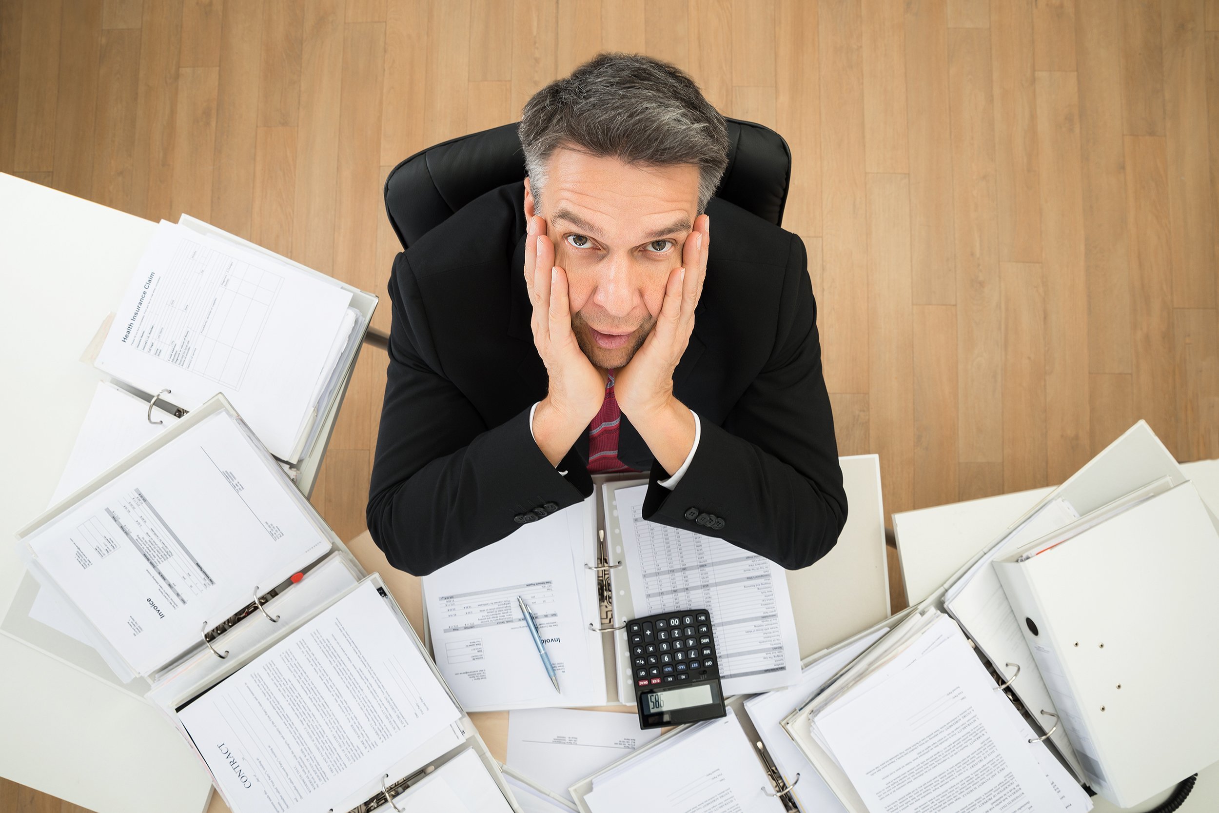 worried mature businessman looking up with hands on cheek