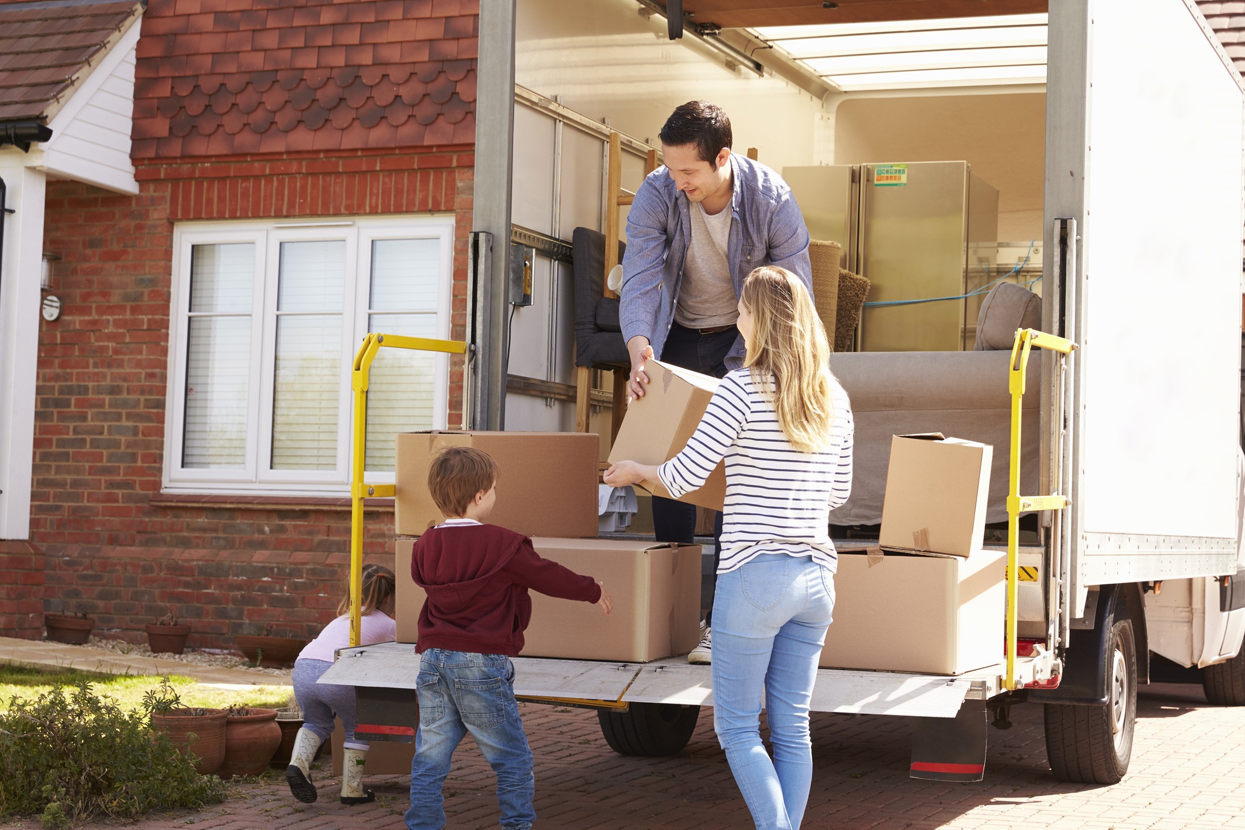 family unpacking moving in boxes from removal truck