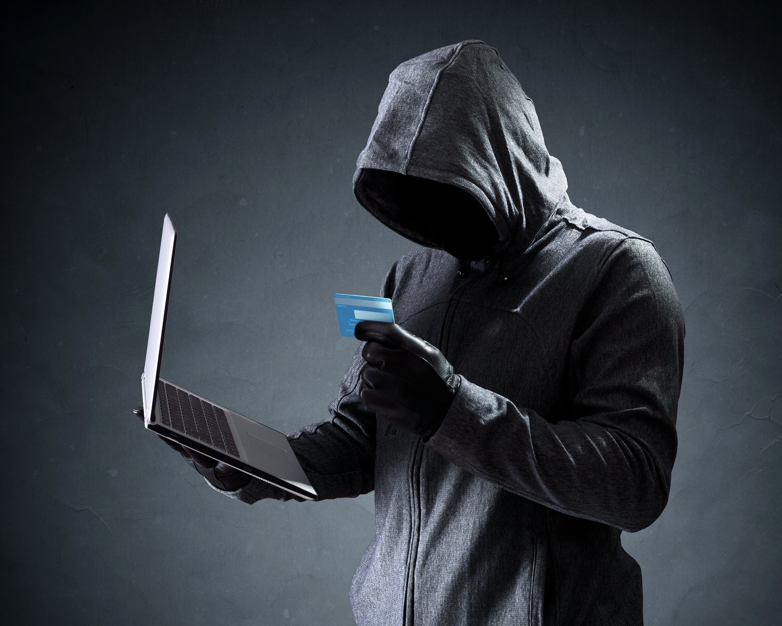 computer hacker with credit card stealing data from a laptop