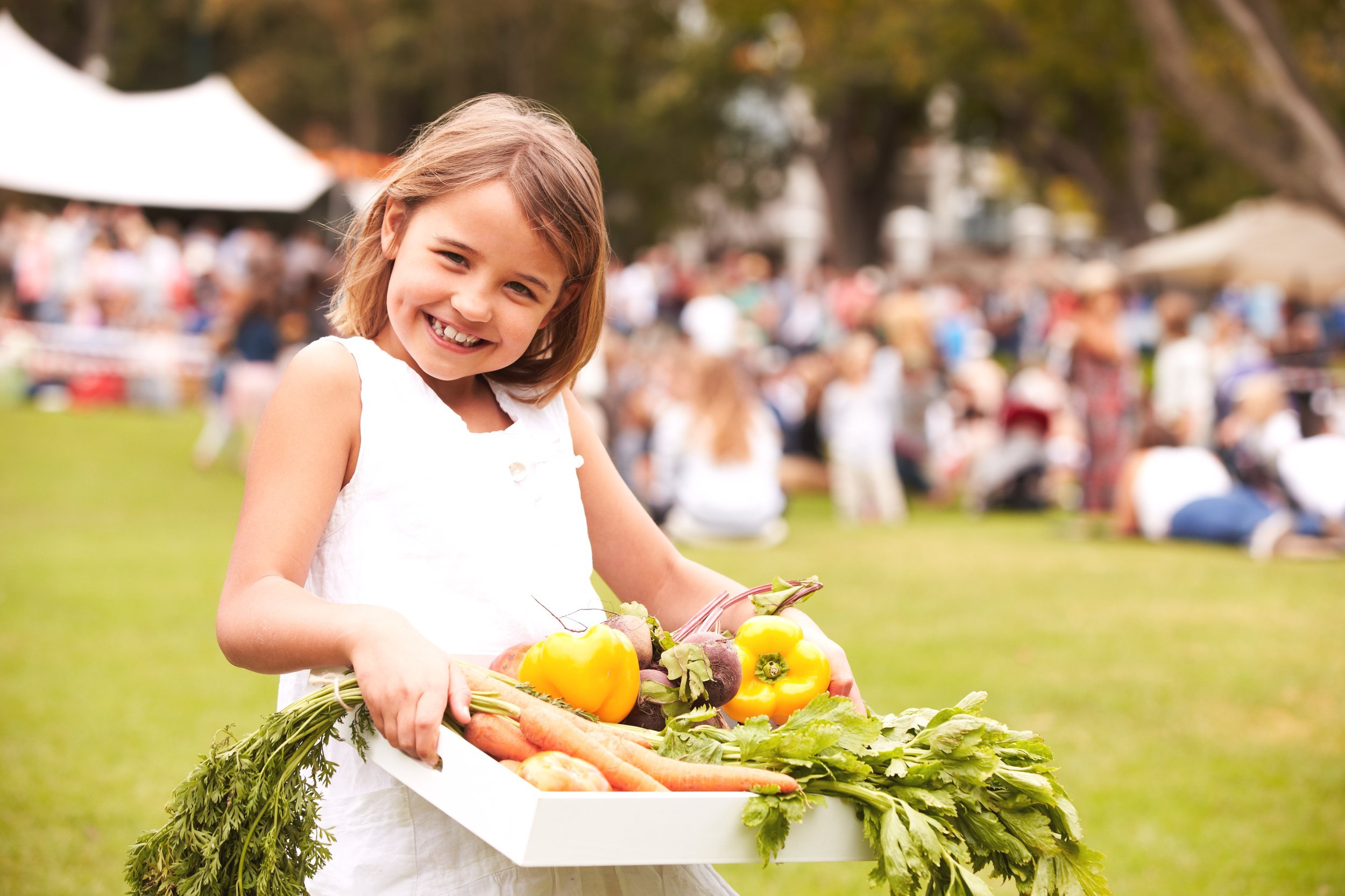 Girl with fresh produce at outdoor farmers market