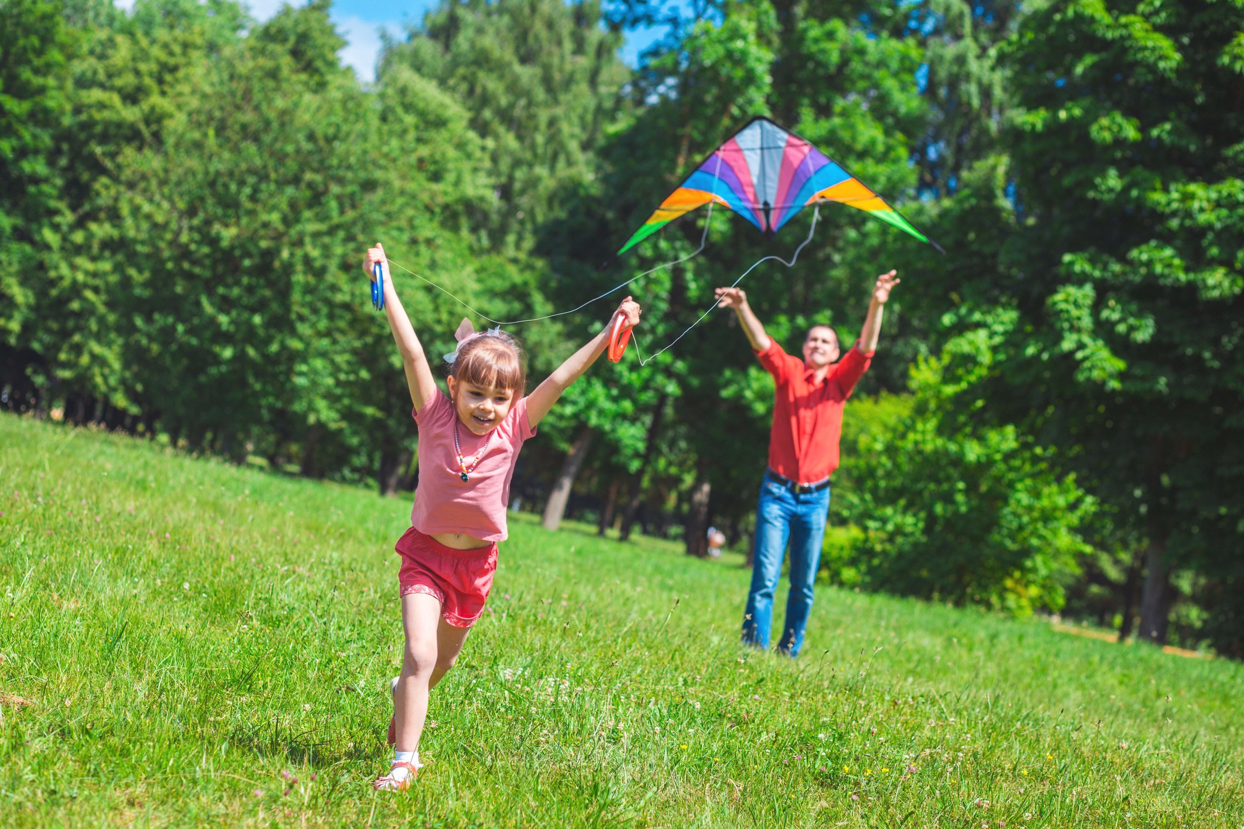 Young girl and father flying a kite outside