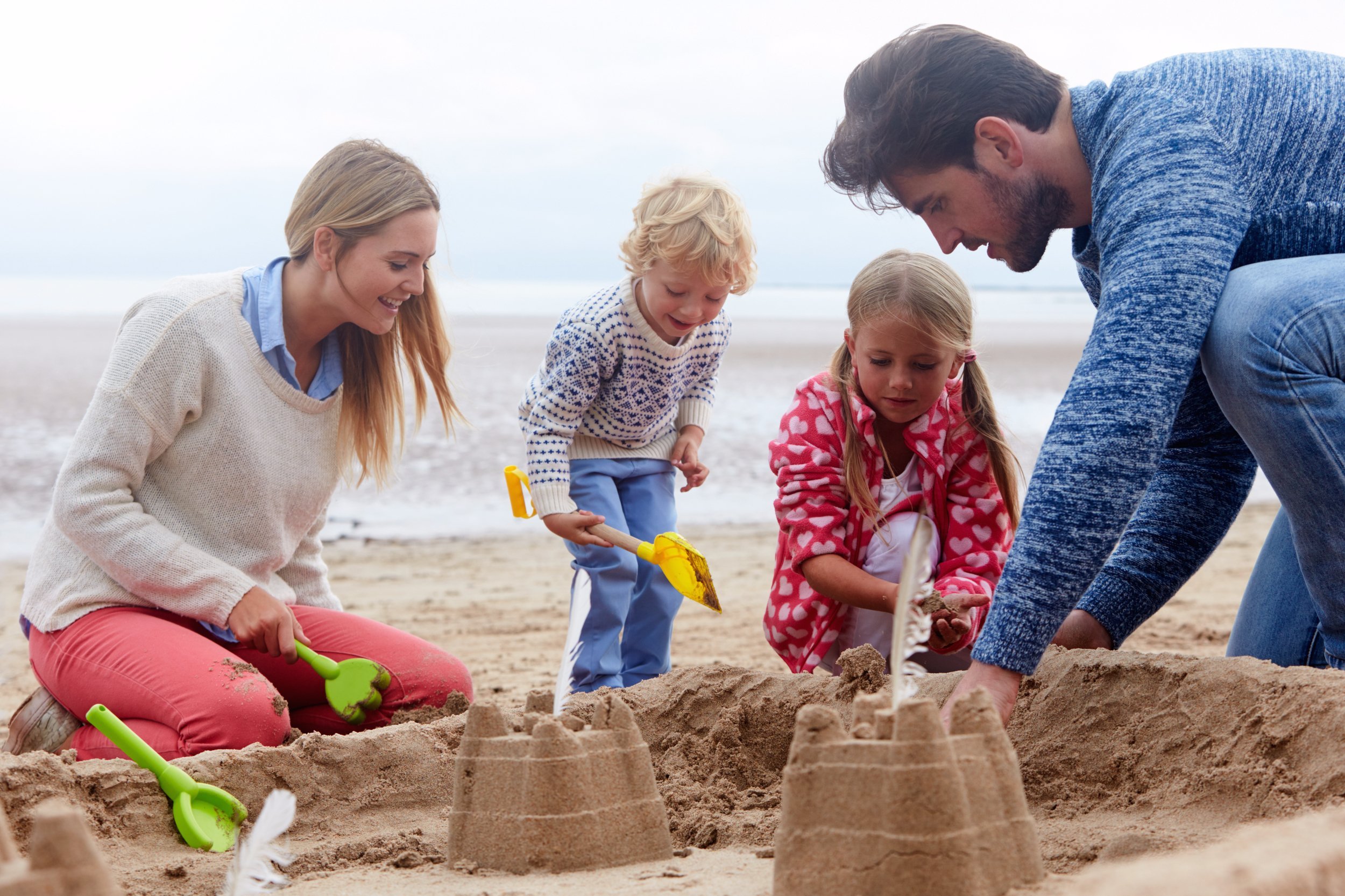 Family building a sandcastle on the beach
