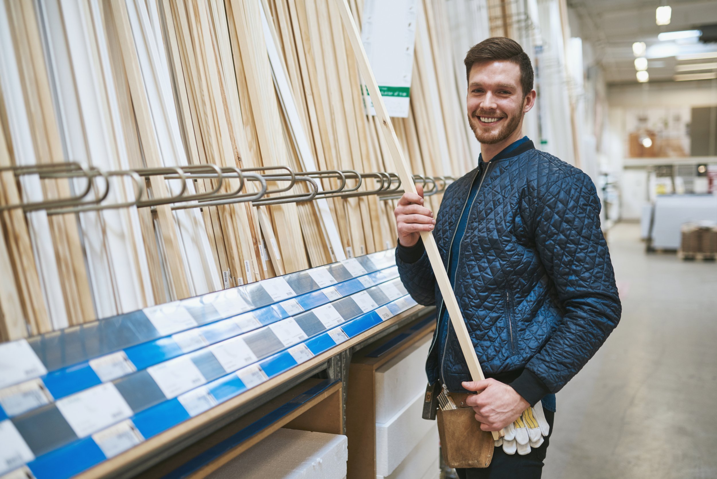 Happy handyman standing in a hardware store purchasing cut timber