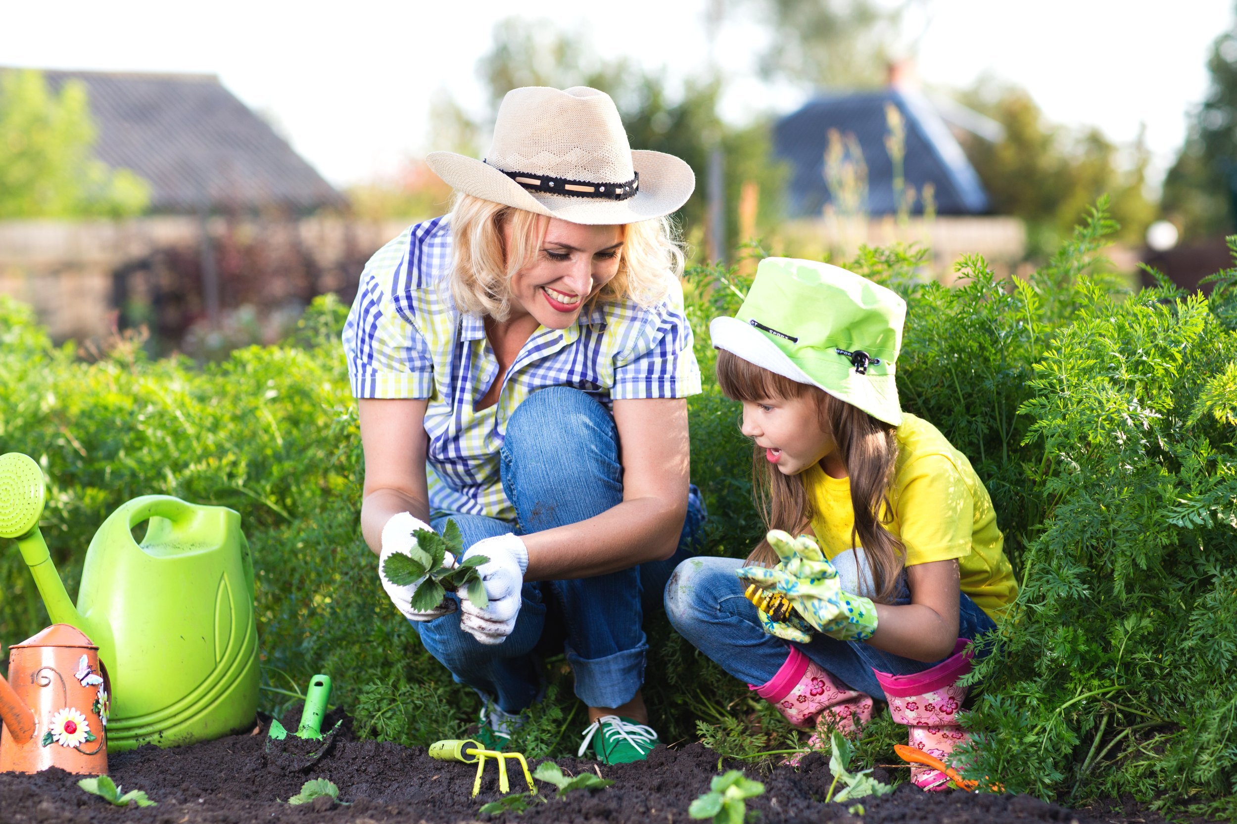 Mother and daughter child planting seedlings in summer time