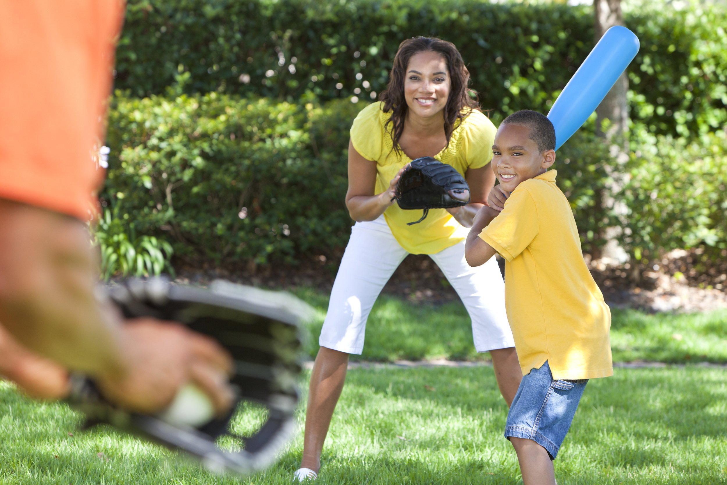 African American family playing baseball together outside