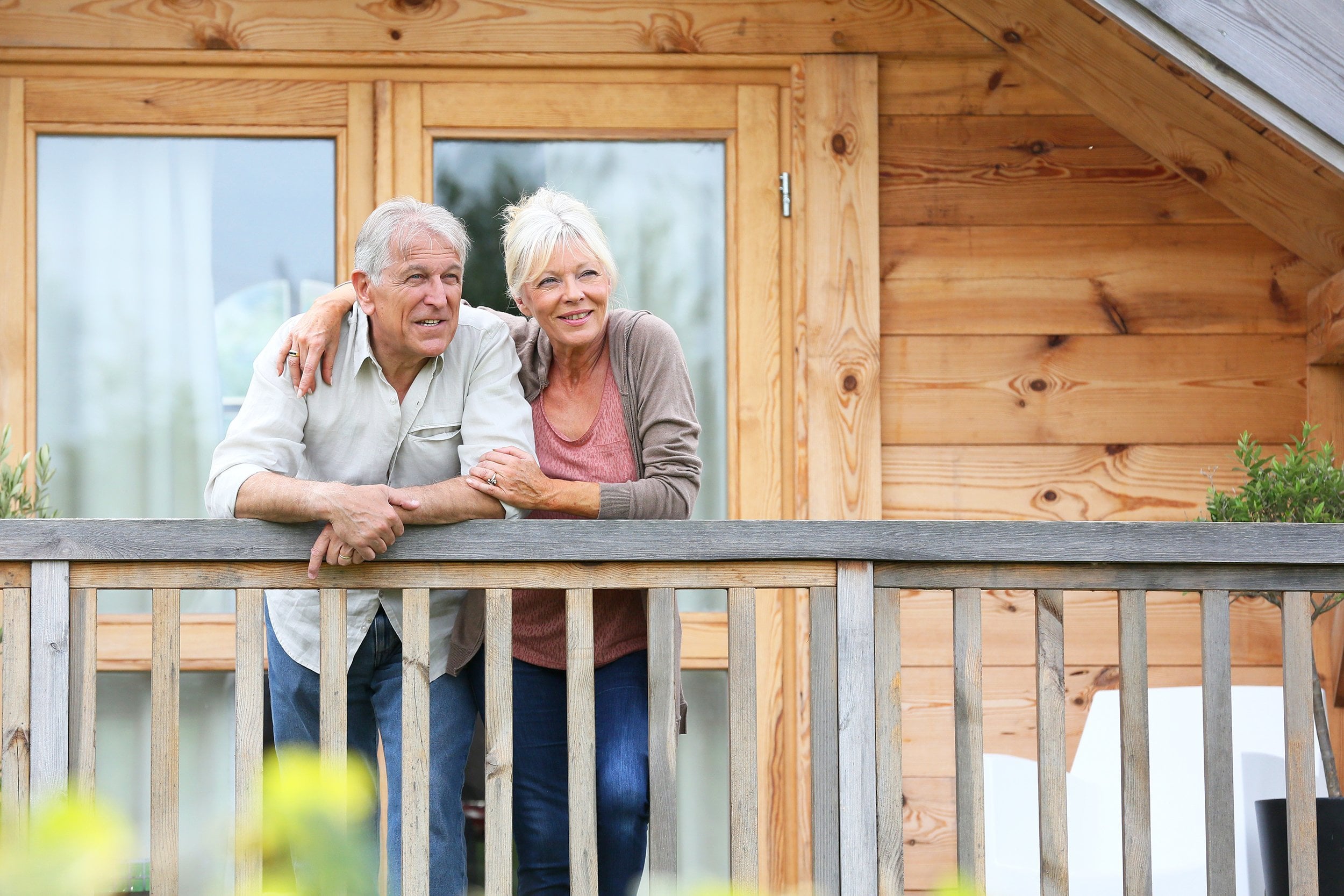 senior couple standing outside log cabin in countryside