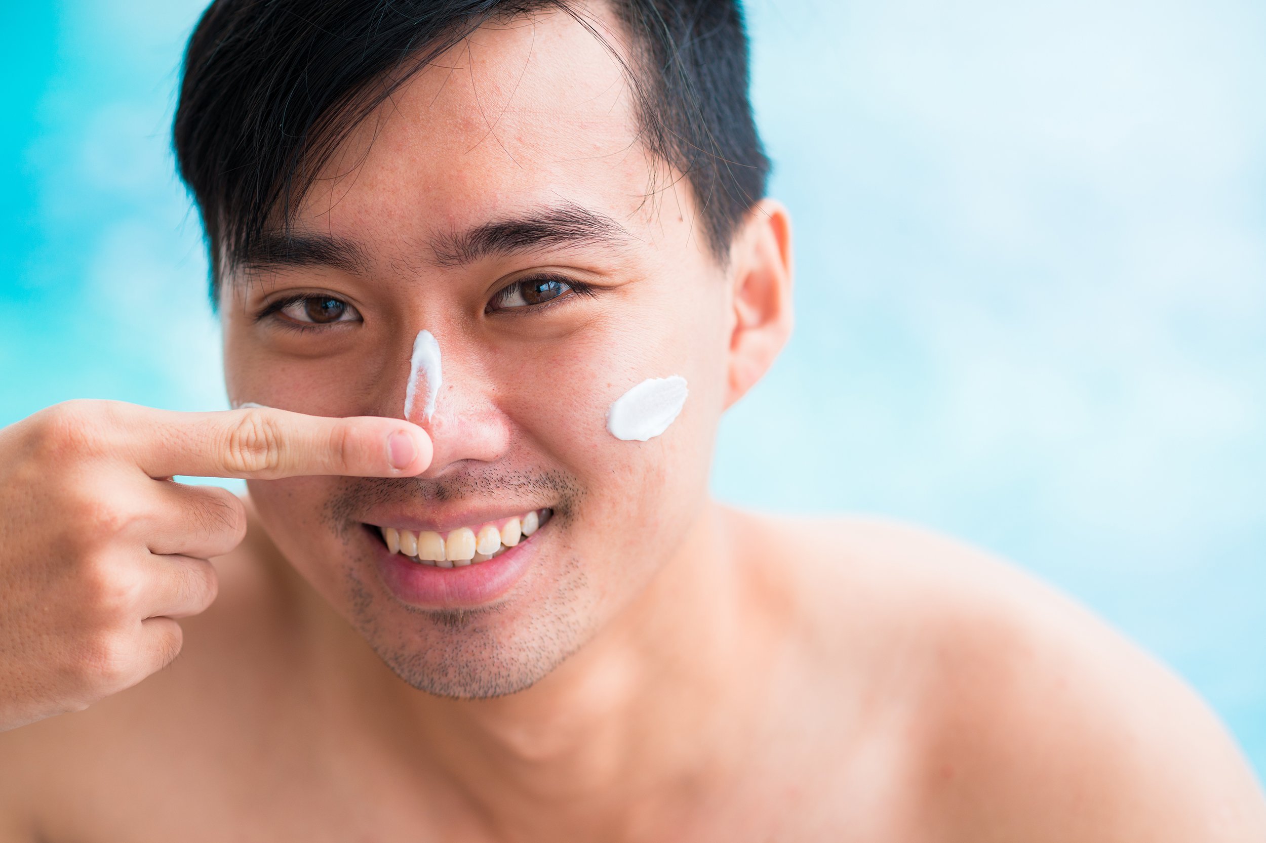 handsome man applying sunscreen on his face
