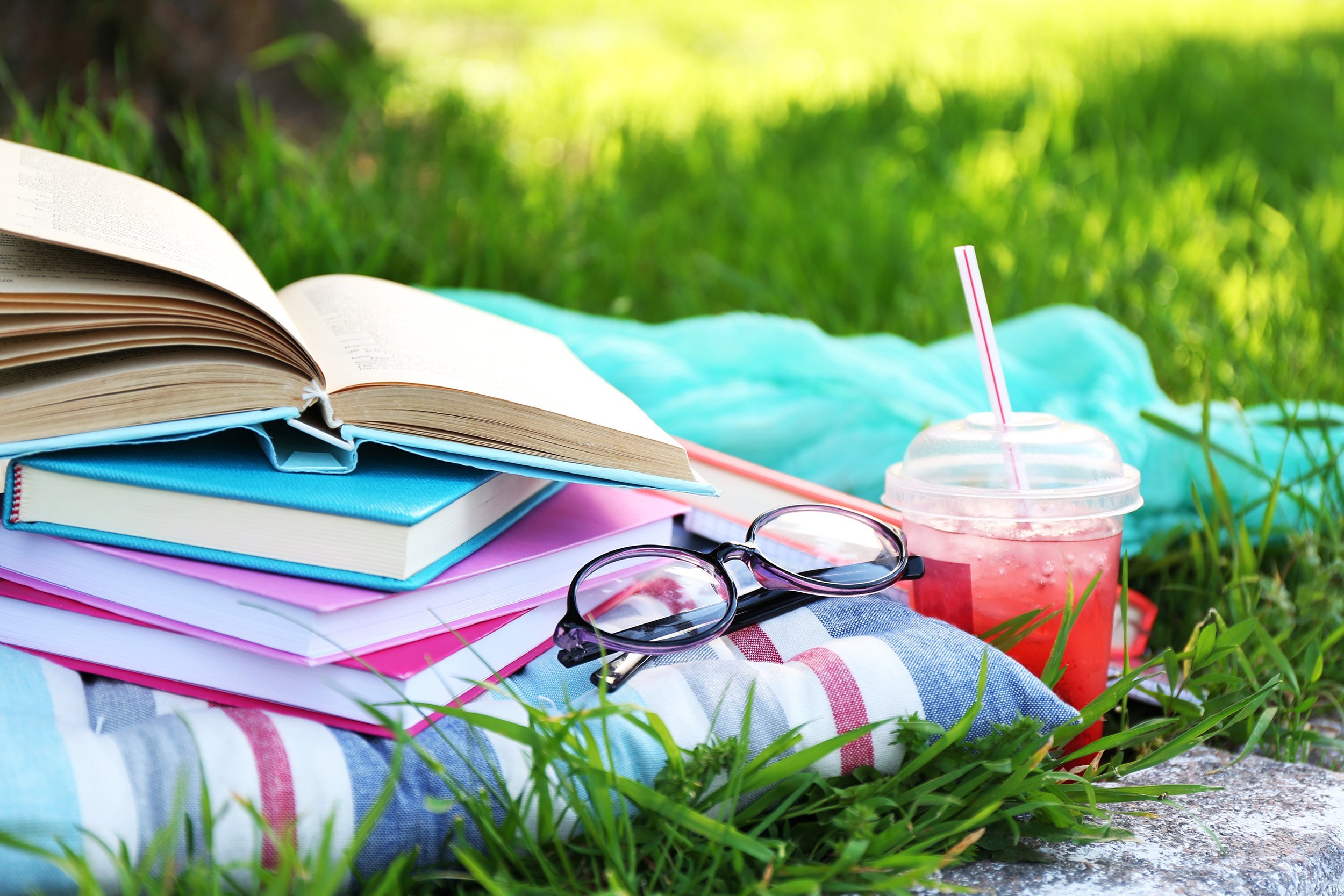 books, glasses, and drink on grass