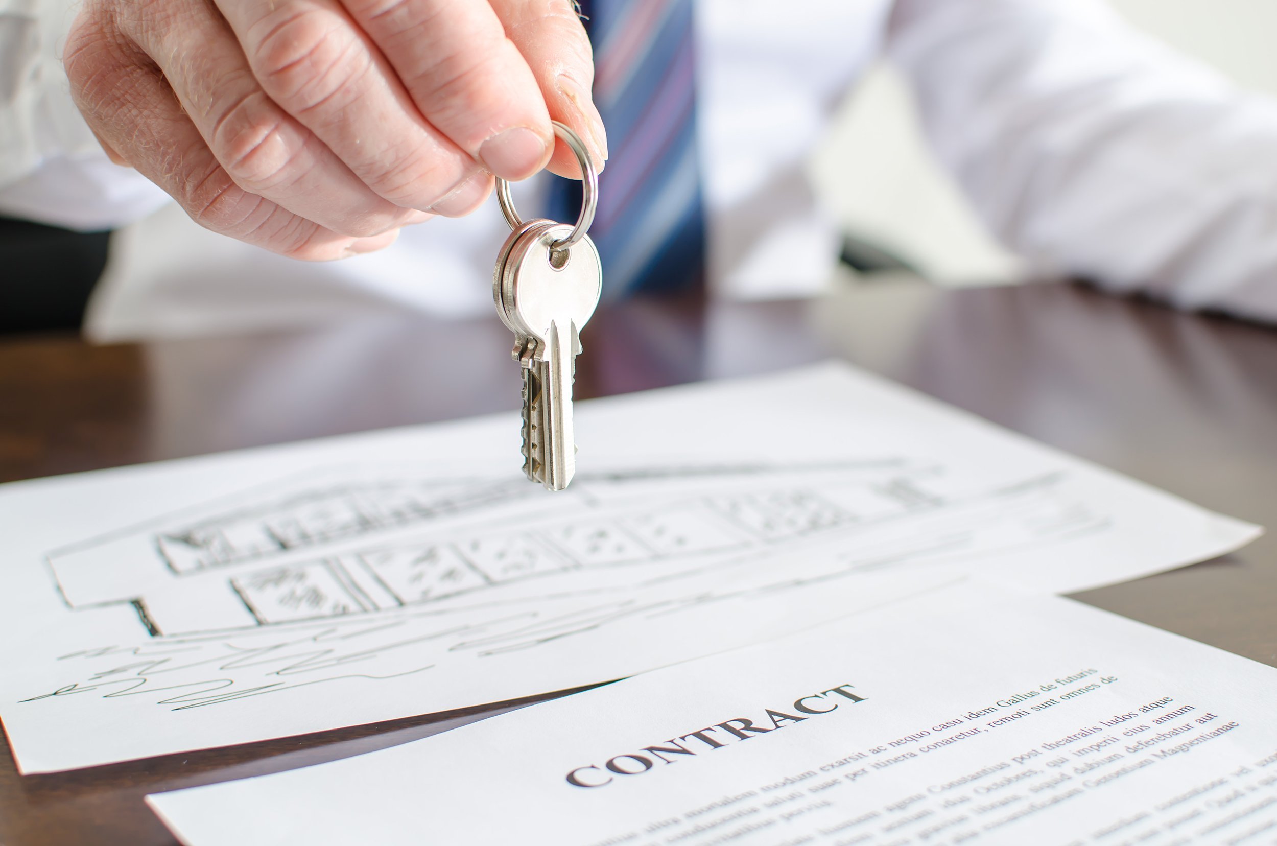 estate agent holding house keys over a contract