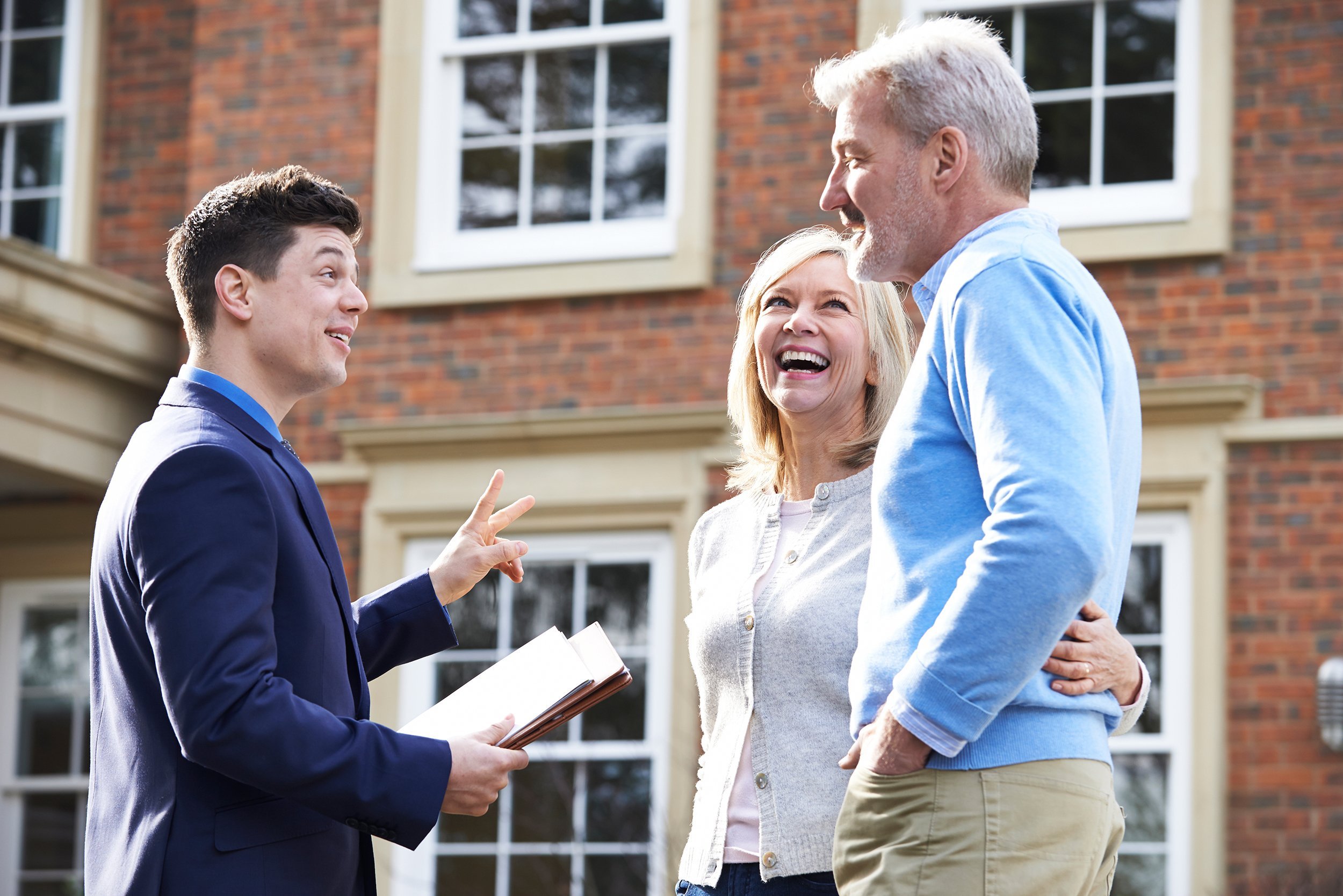 realtor showing mature couple around house for sale