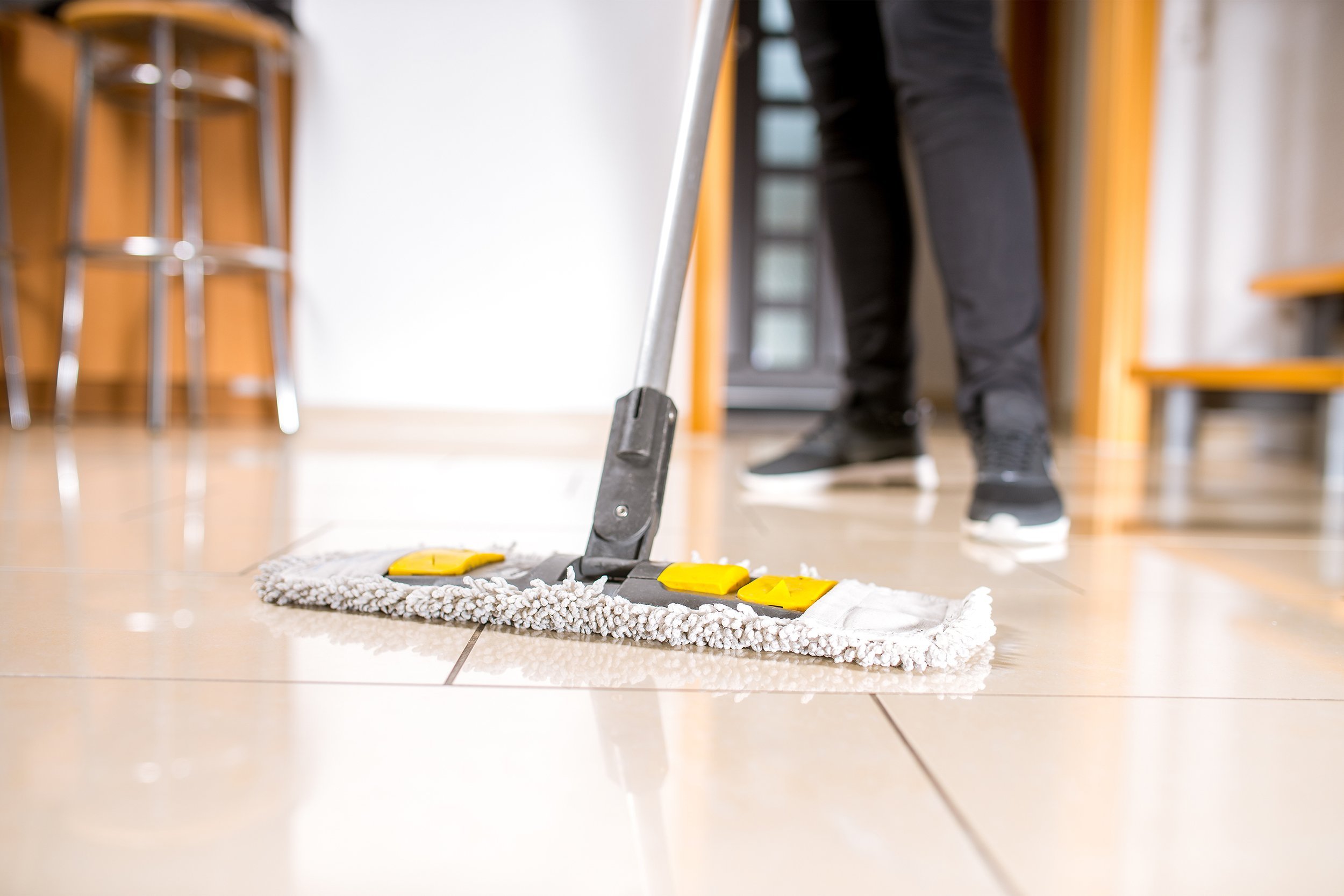 person cleaning the tile floor with swiper