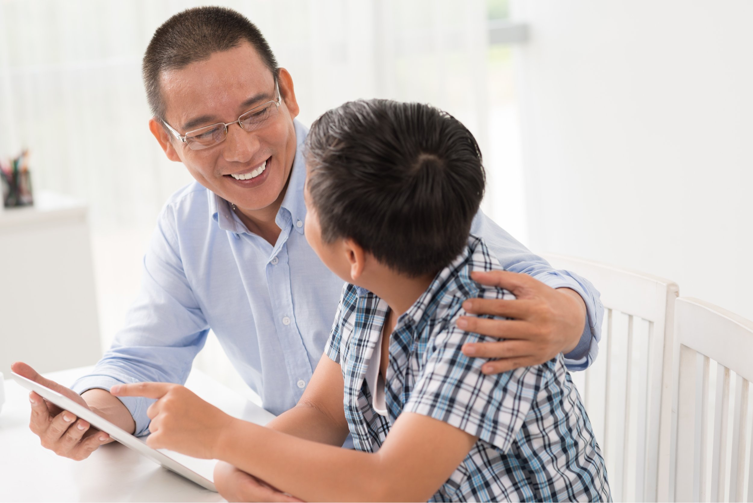 Asian father and son talking and using digital tablet
