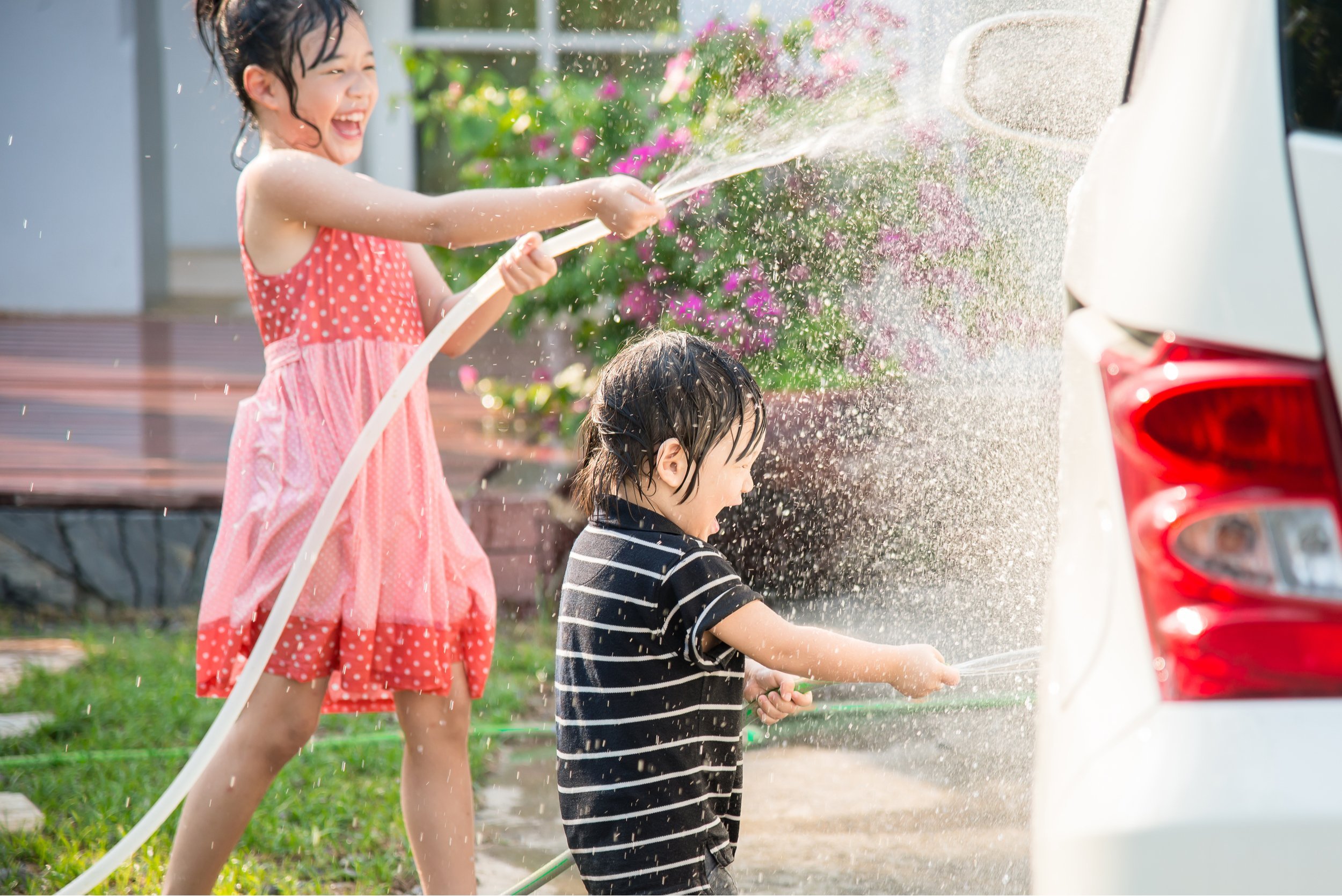 Asian children washing car in the garden
