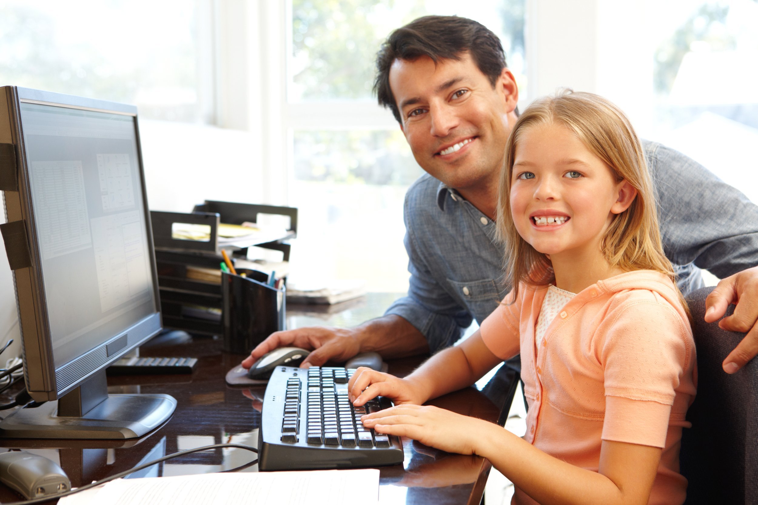 Father and daughter using computer in home office
