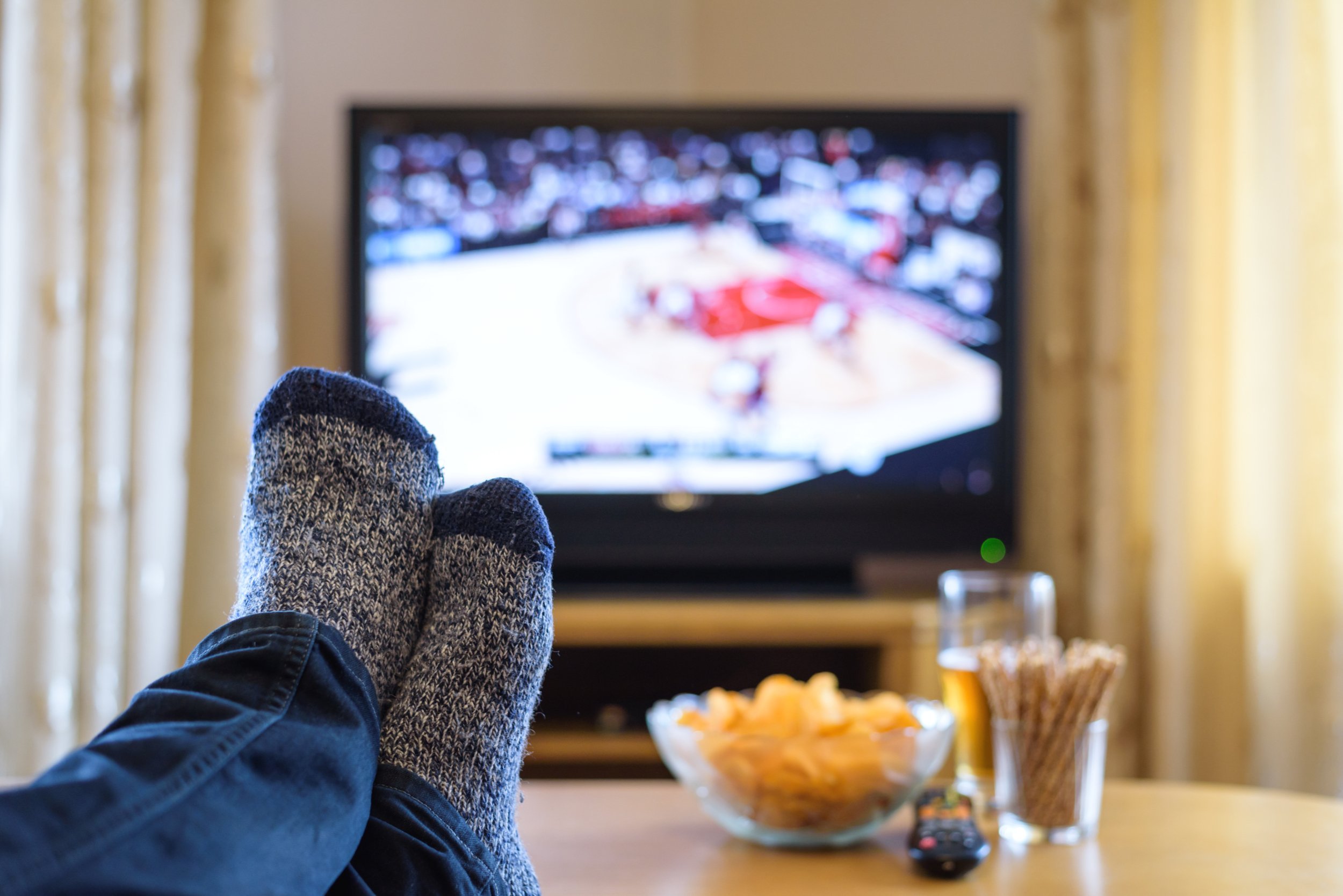 Watching sports with feet on table and snacks