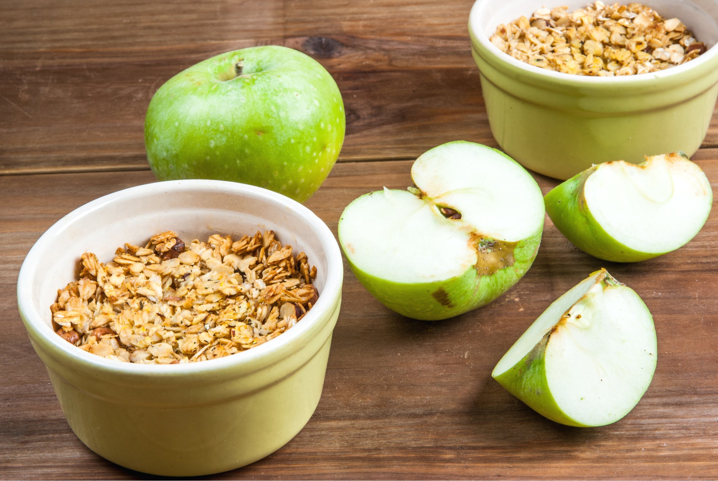Freshly made autumn apple crumble with fresh green apples on a wooden table