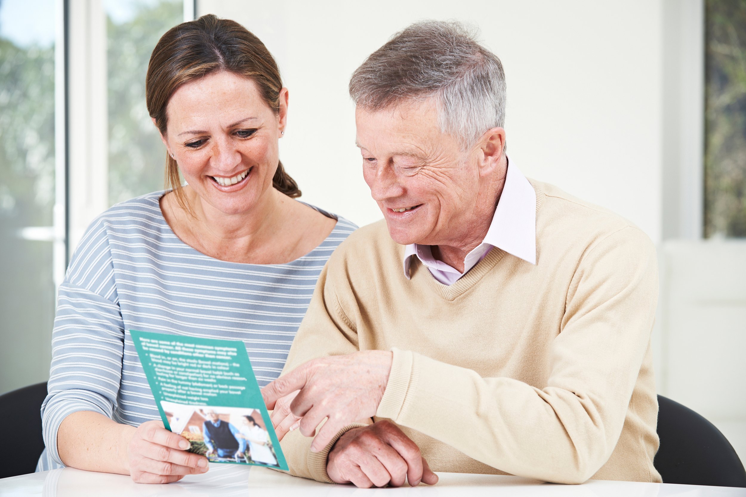 senior man with adult daughter looking at brochure for retirement home