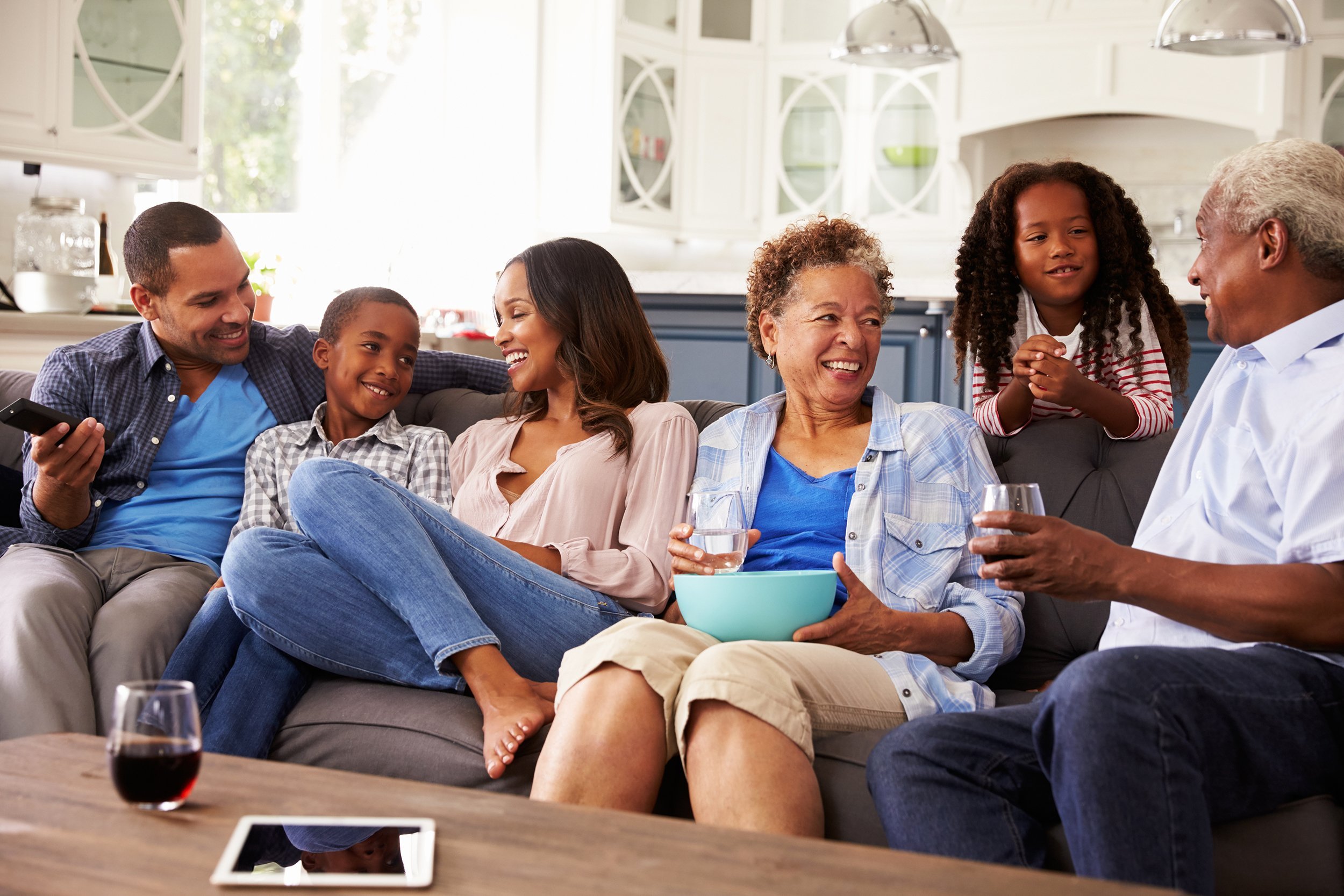 multi generation African American family talking together while watching TV