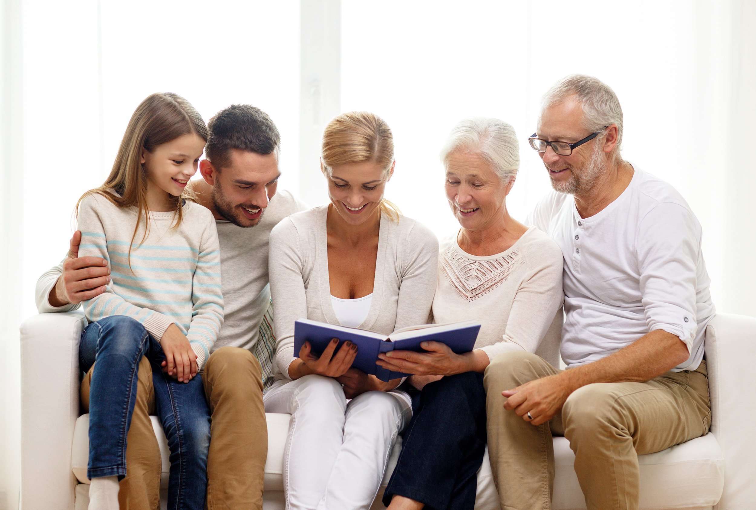 Happy family with book or photo album sitting on couch at home