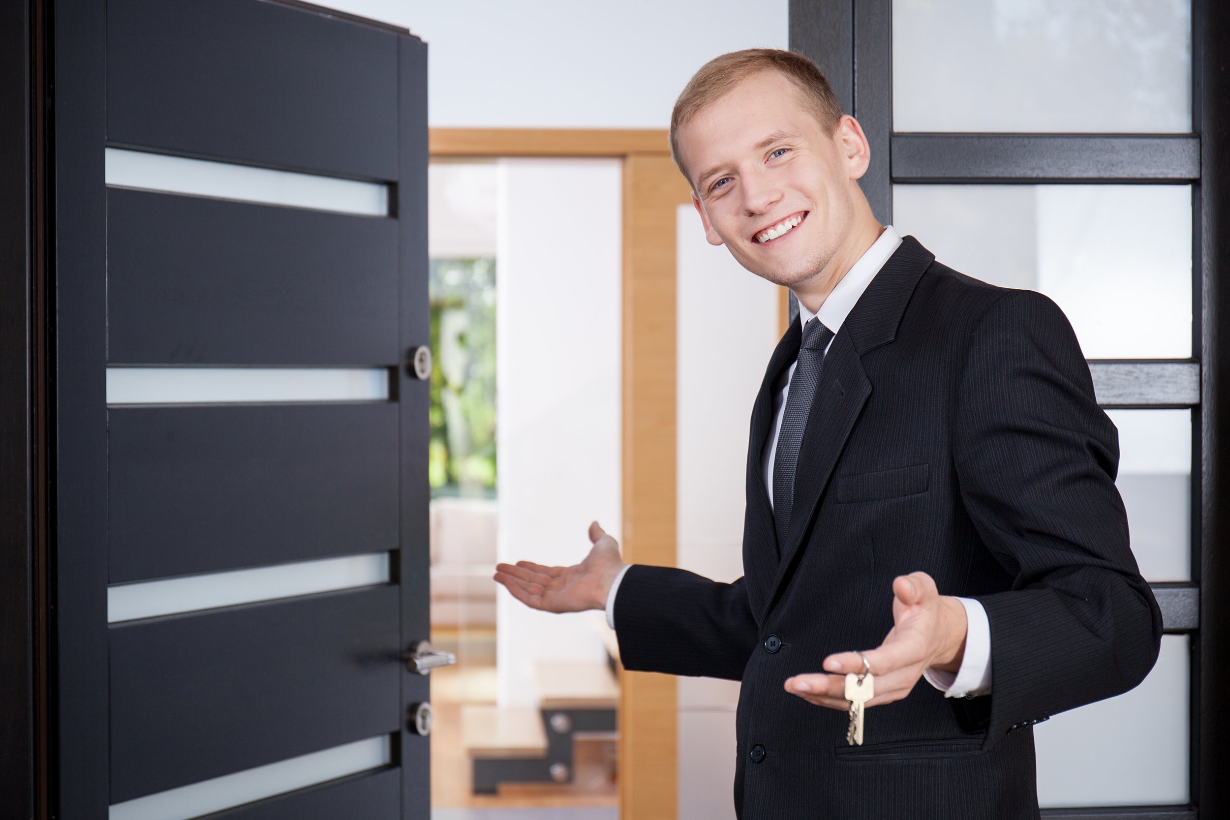 young estate agent invites customers to view house