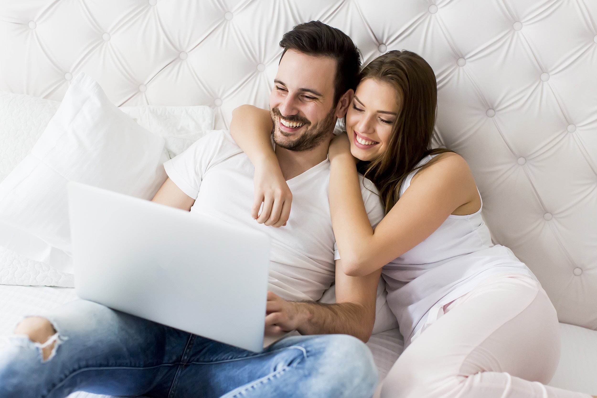 young couple with laptop in the bed