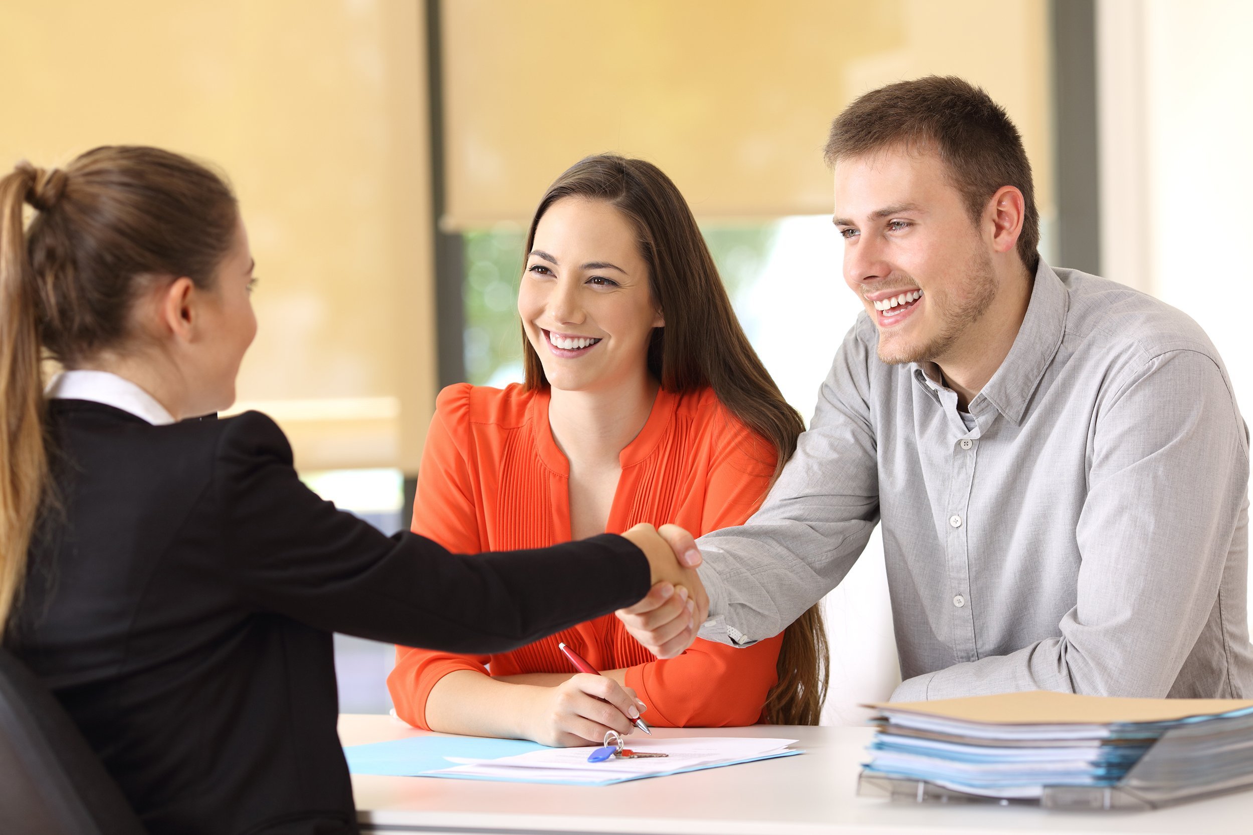 couple of happy customers handshaking with worker after a deal at office