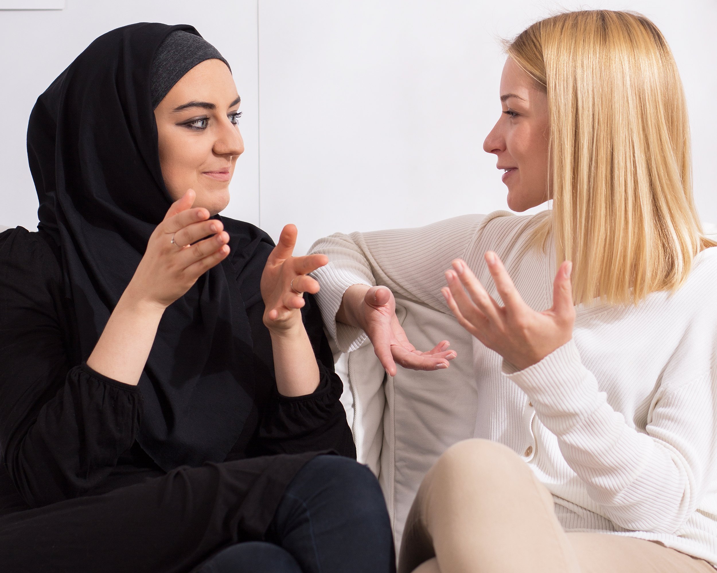 Muslim and Western women talking to each other on the couch