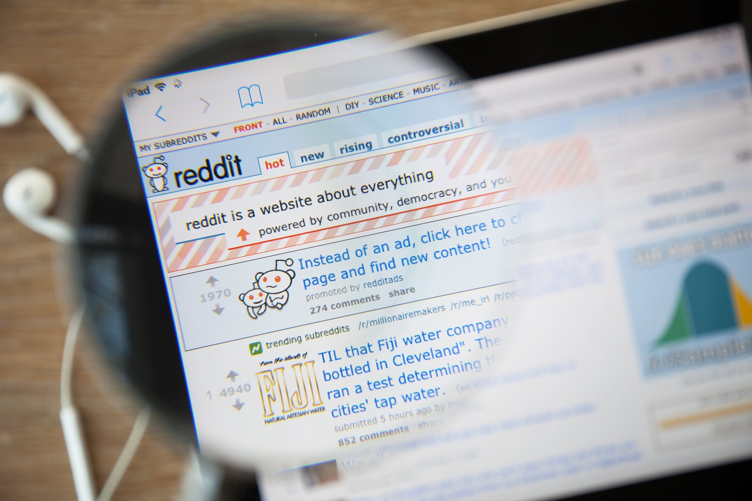 Reddit homepage on a ipad monitor screen through a magnifying glass