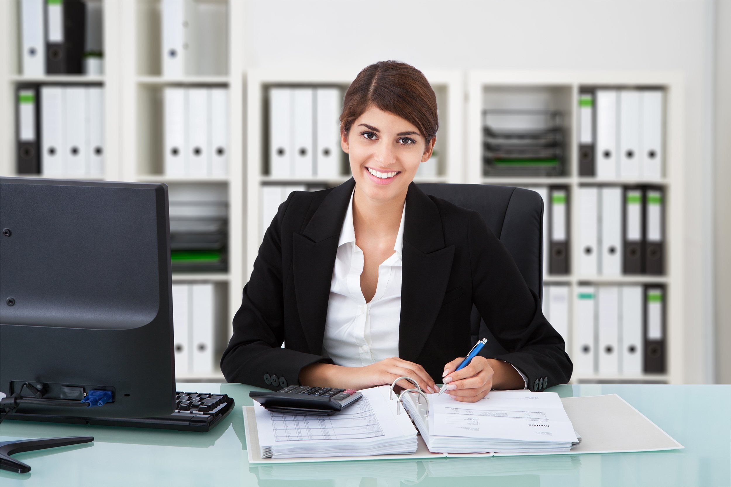 confident female accountant writing on documents at desk in office