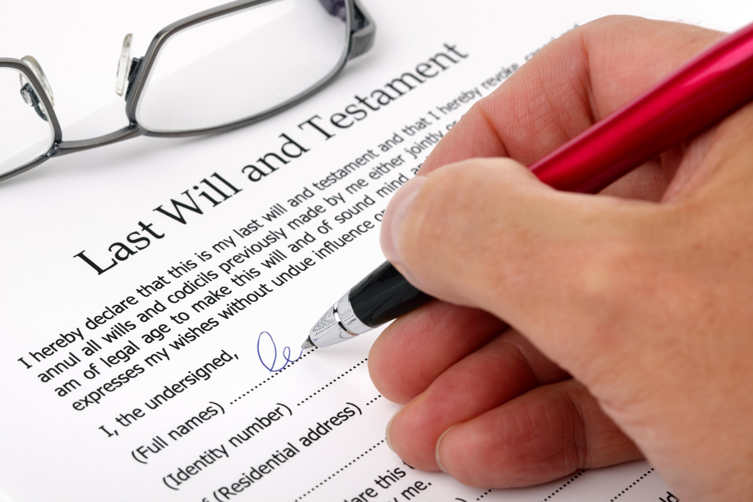 close up of hand signing a Last Will and Testament document
