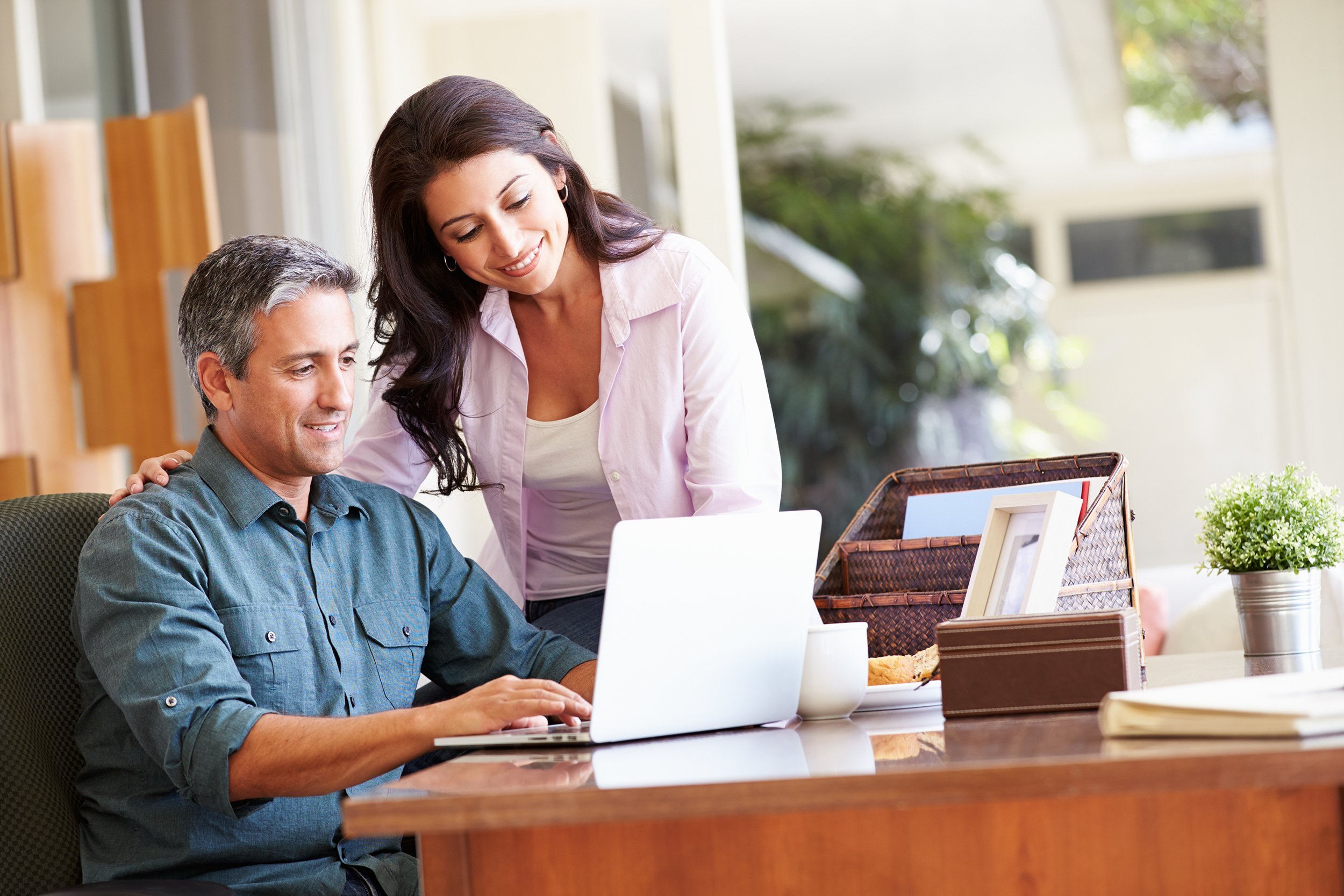 hispanic couple using laptop on desk at home
