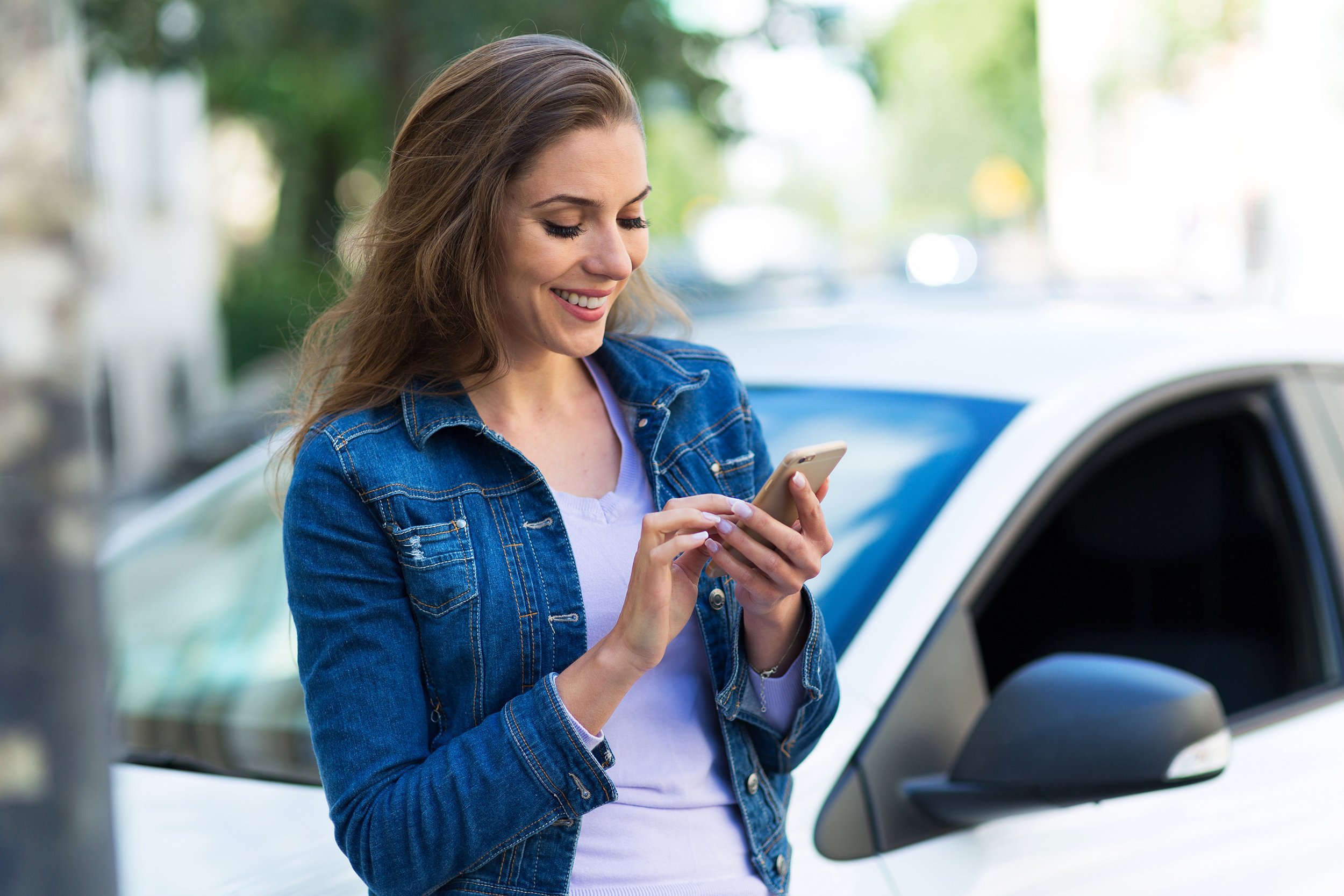 woman using mobile phone near car