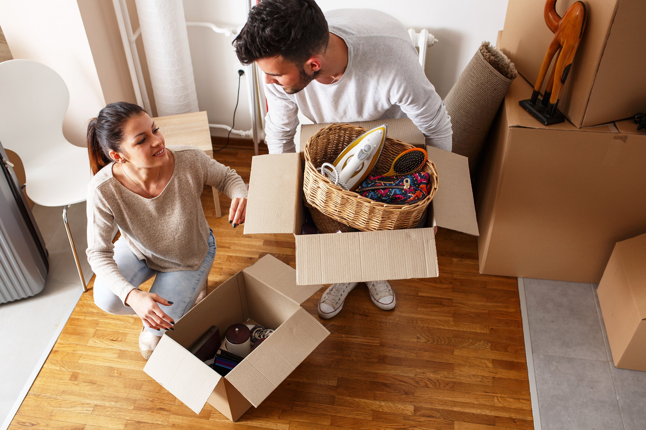 young couple unpacking cardboard boxes at new home
