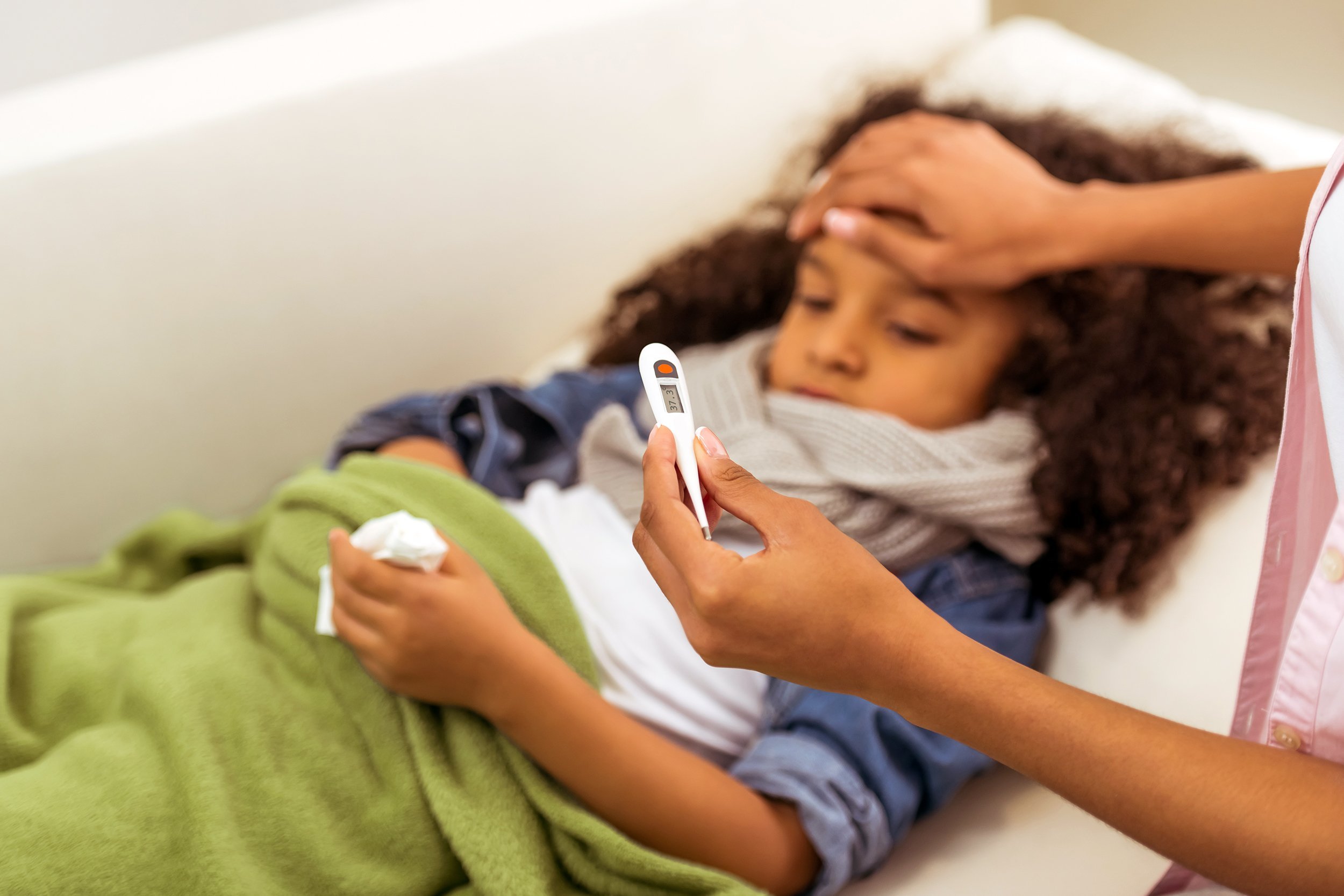 little African American girl with scarf on her neck is ill, lying in bed with temperature