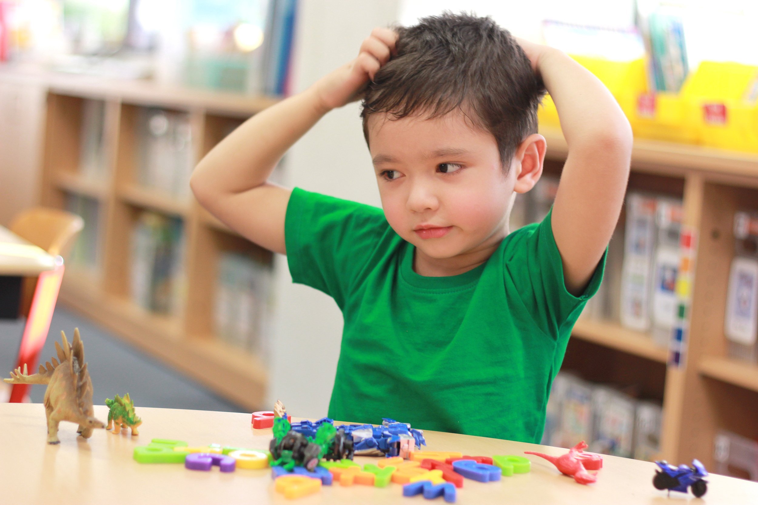 little boy in green skirt scratching his head