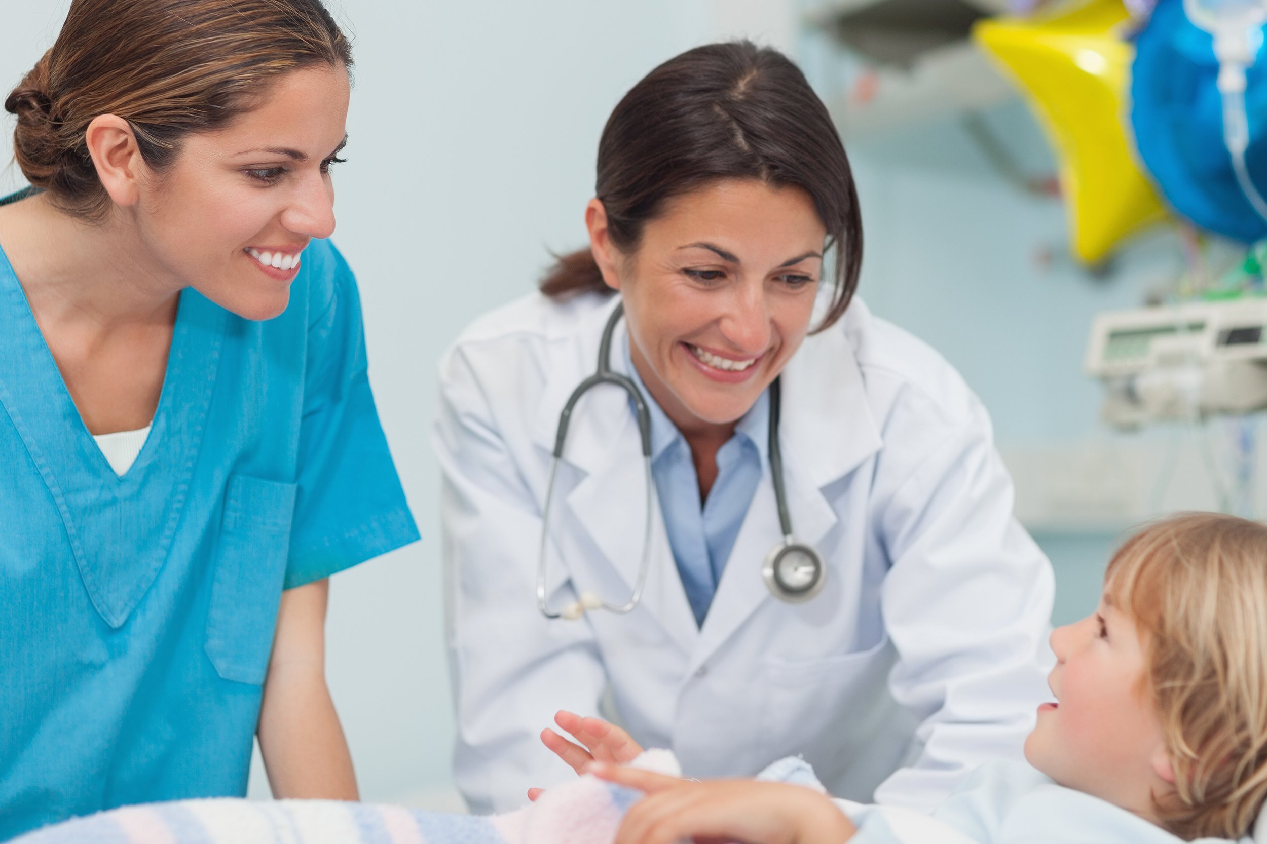 nurse and doctor smiling to a child in hospital ward
