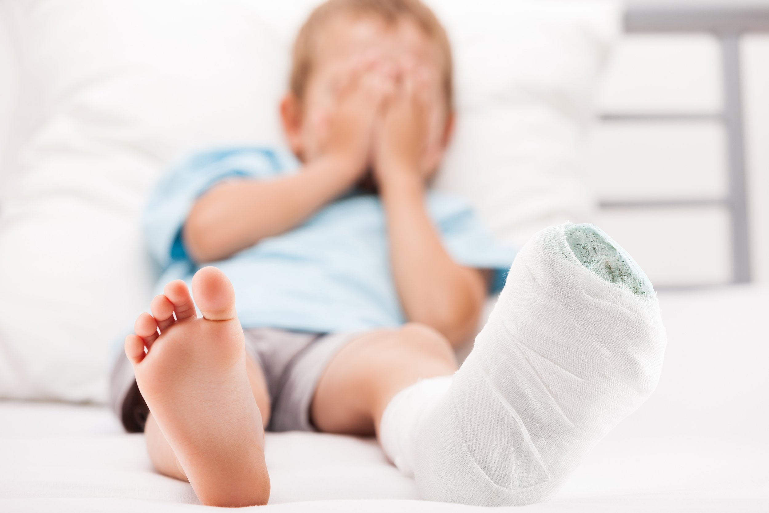 little child boy with plaster bandage on leg heel in bed