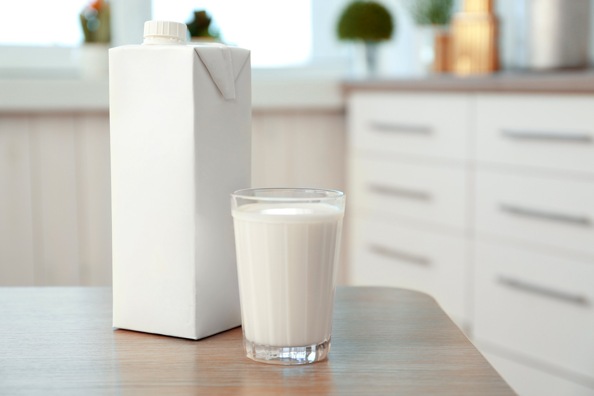Carton of milk next to a glass of milk