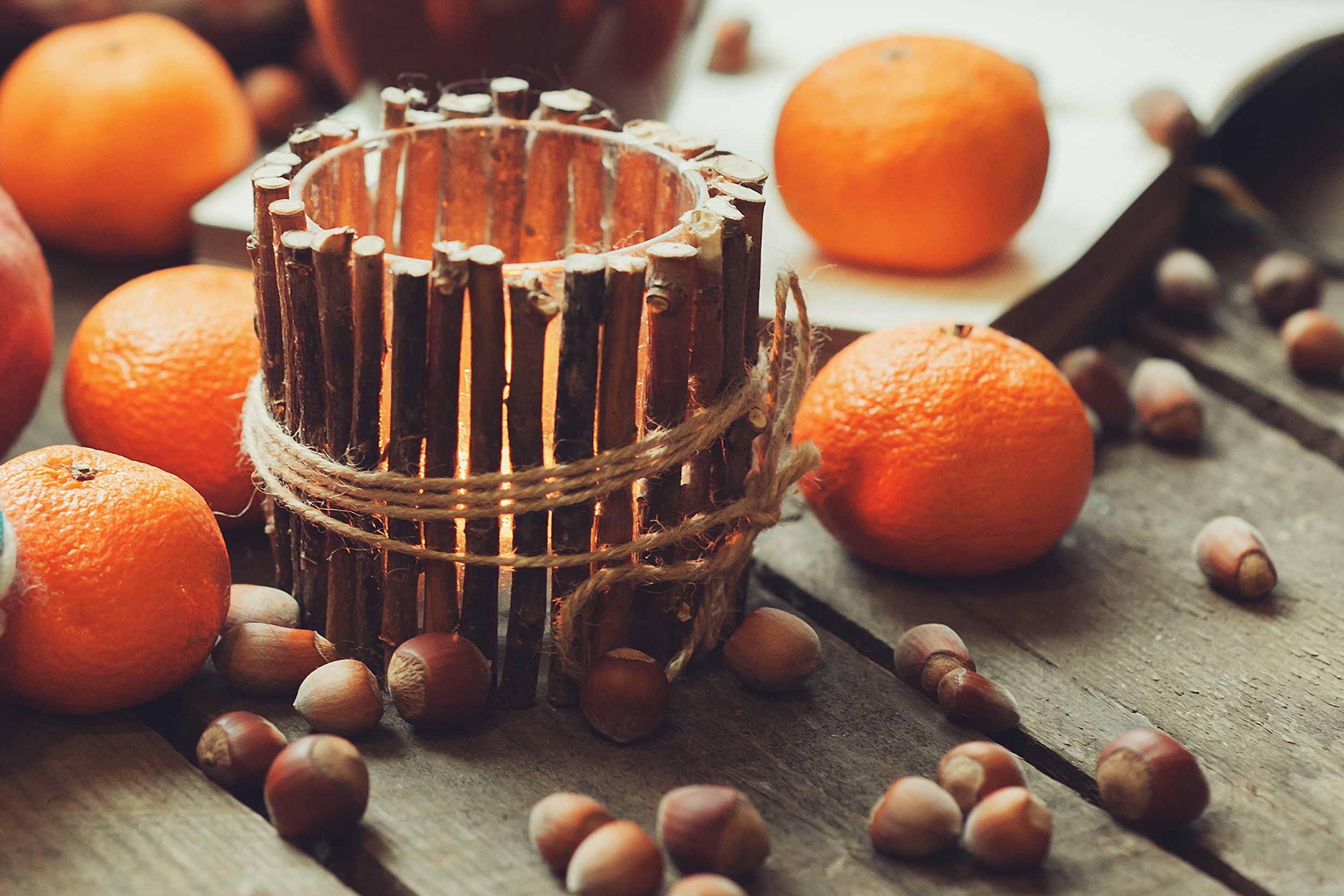 candle decorated with twigs, acorns, oranges
